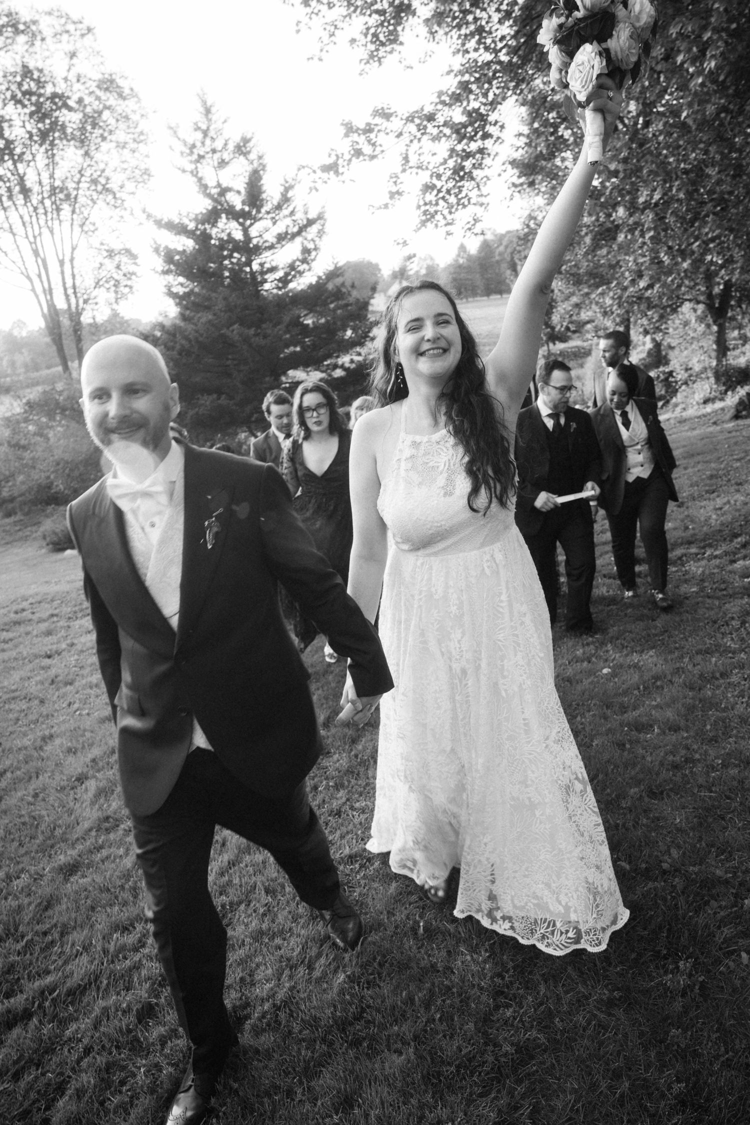 Celebratory black and white photo of newlyweds walking outdoors with pure joy and excitement.