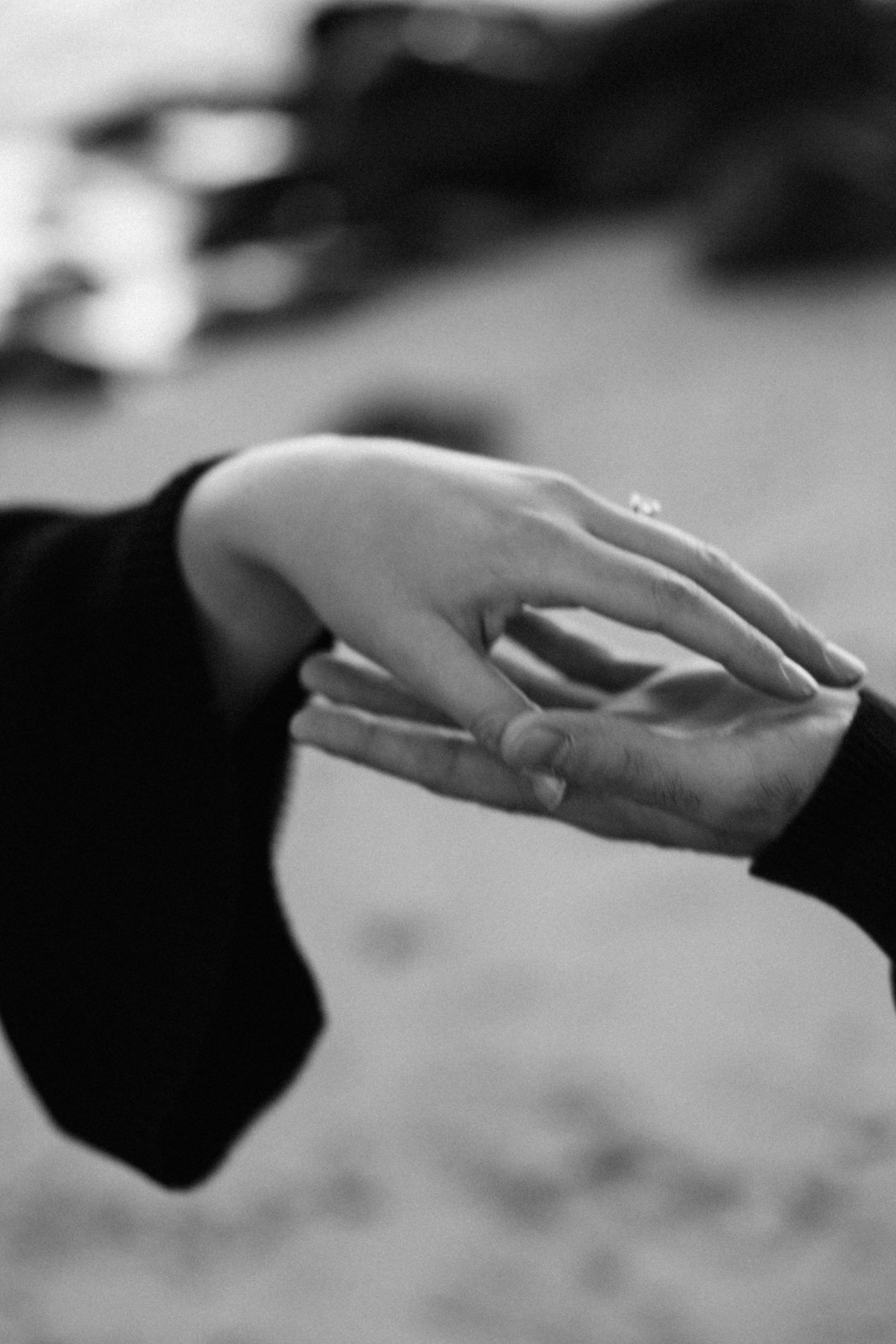Close-up black and white photo of hands gently touching.