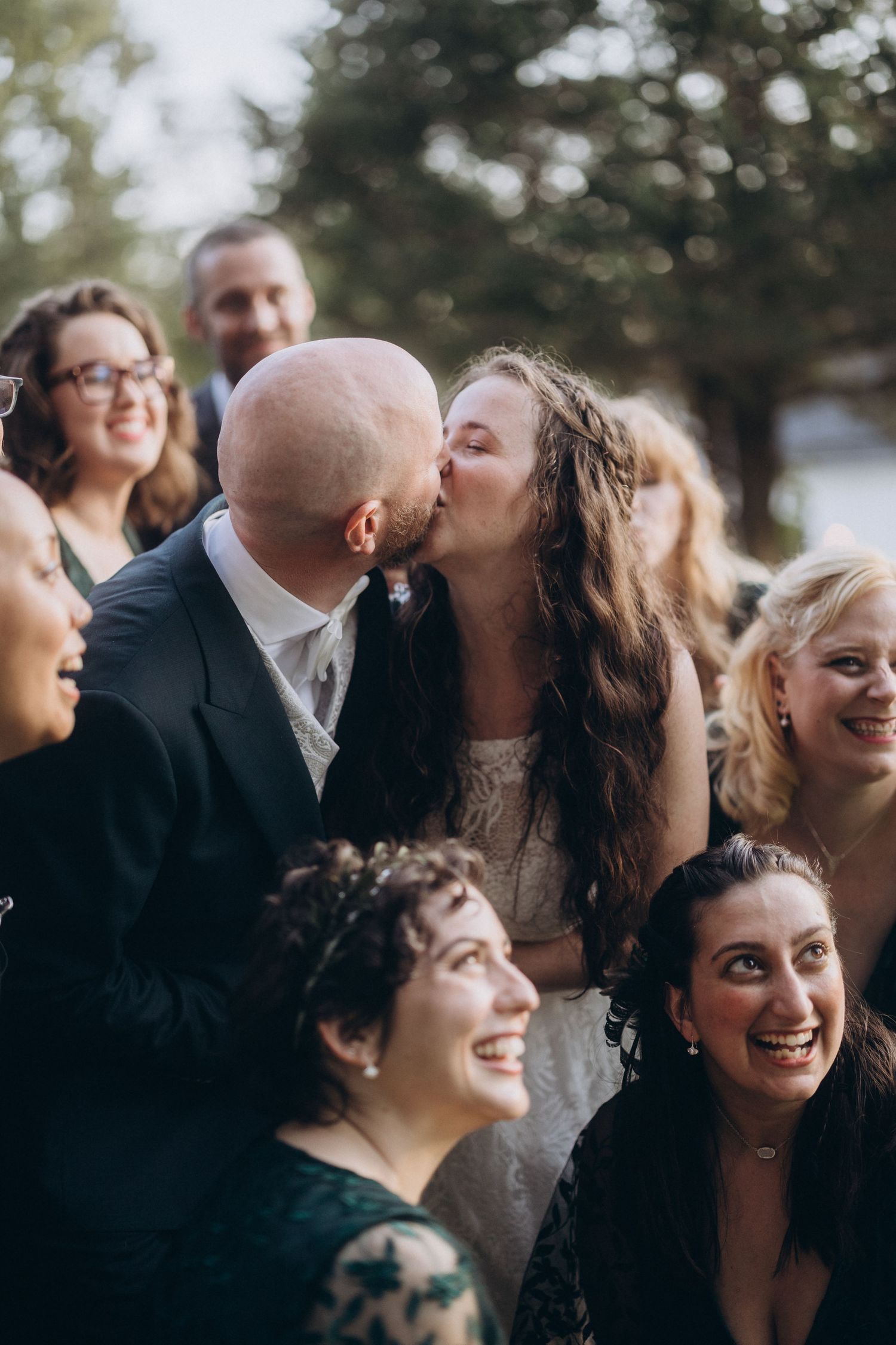 Candid wedding moment surrounded by joyful guests during outdoor celebration.