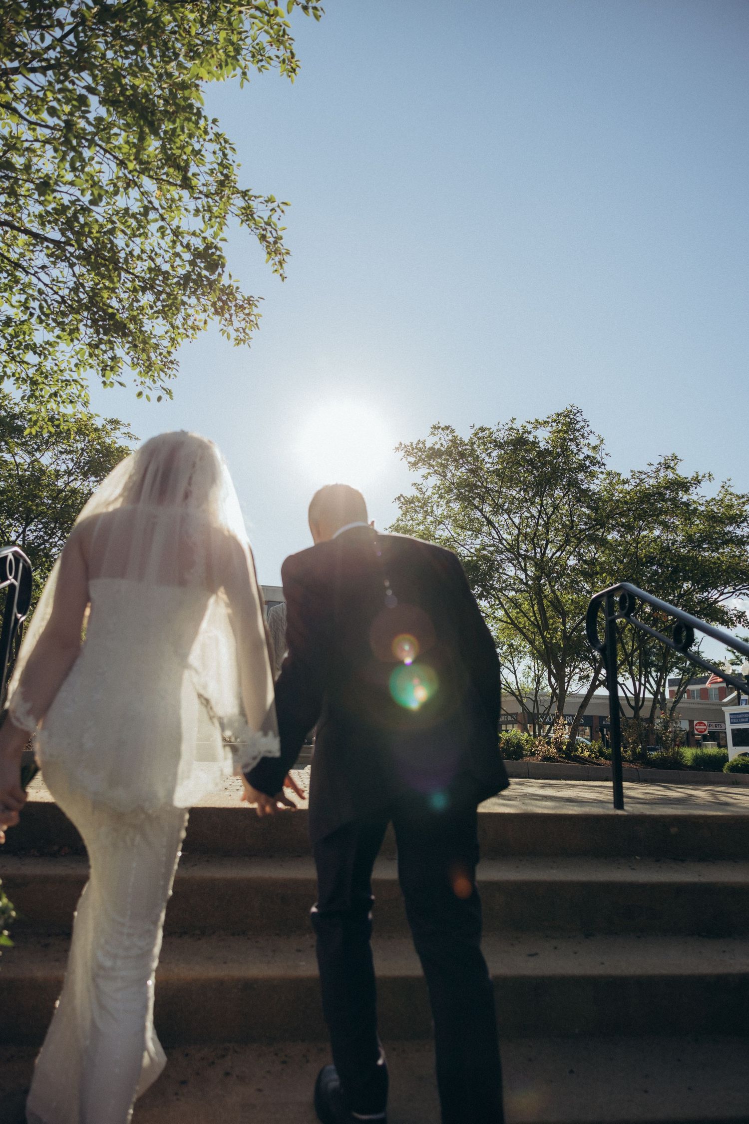 Silhouette of a wedding couple against bright sunlight and trees.