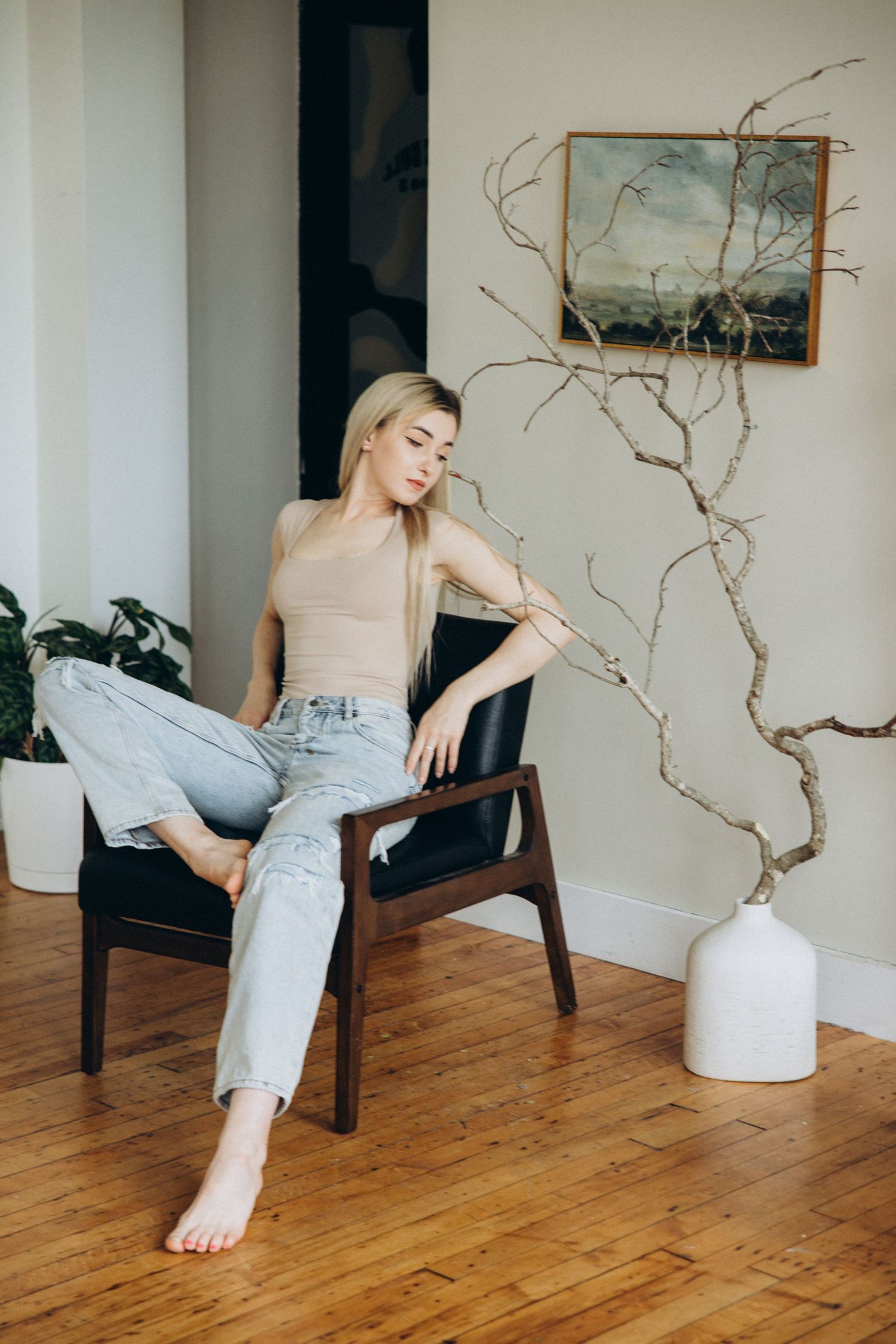 Casual lounging poses in tan top and light pants on wooden floor.