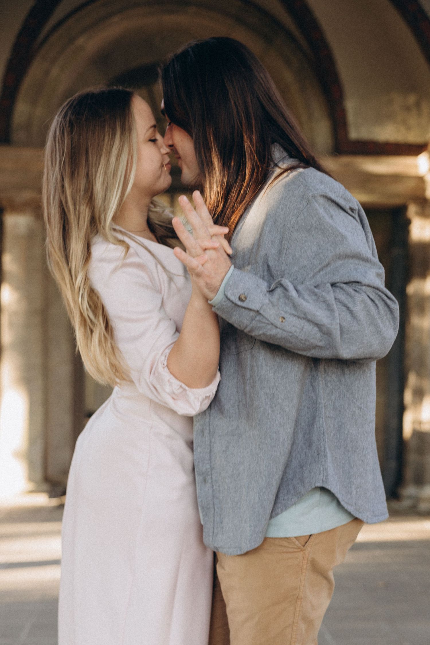 A romantic moment between two people in light and dark clothing under an archway.