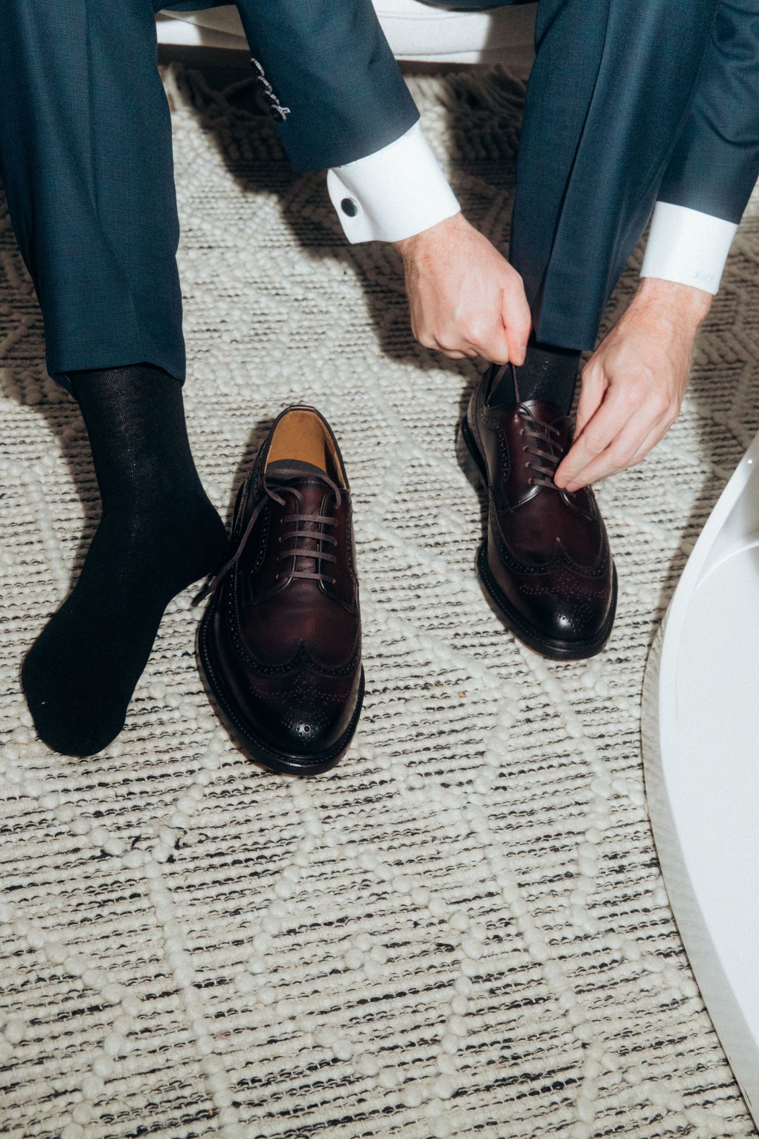 Detail shots of formal dress shoes being put on during wedding preparation.