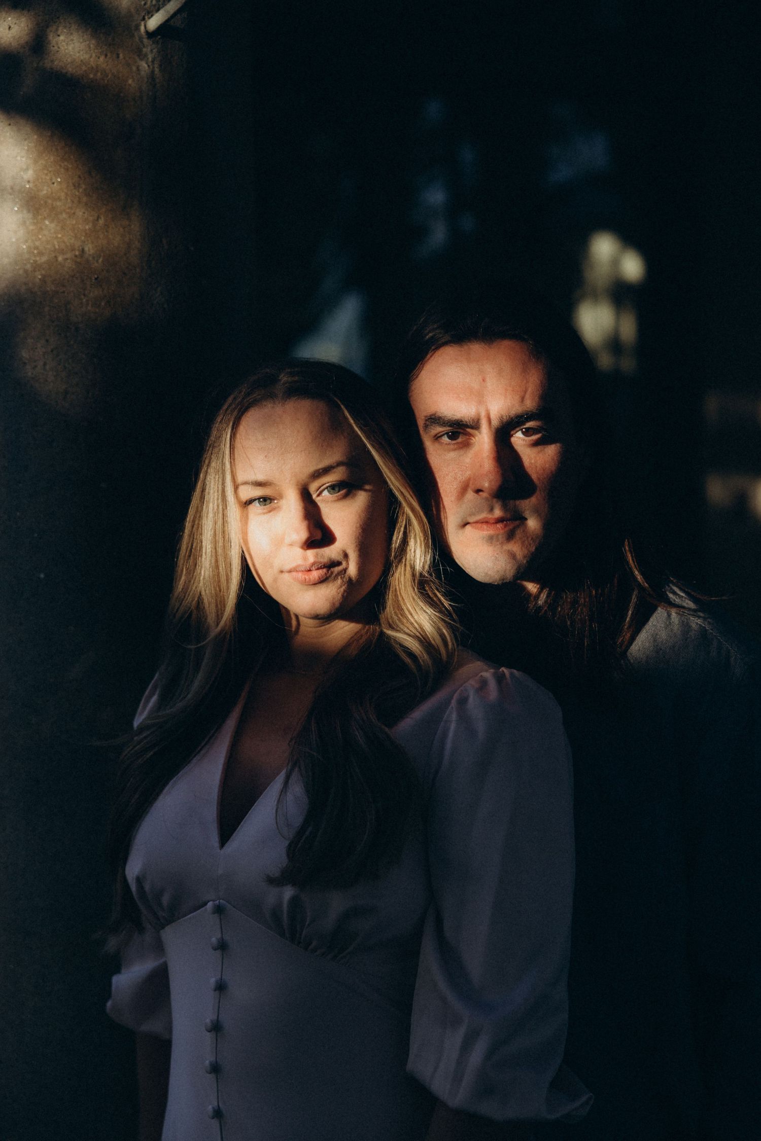 An intimate couple's portrait with dramatic lighting and shadows.