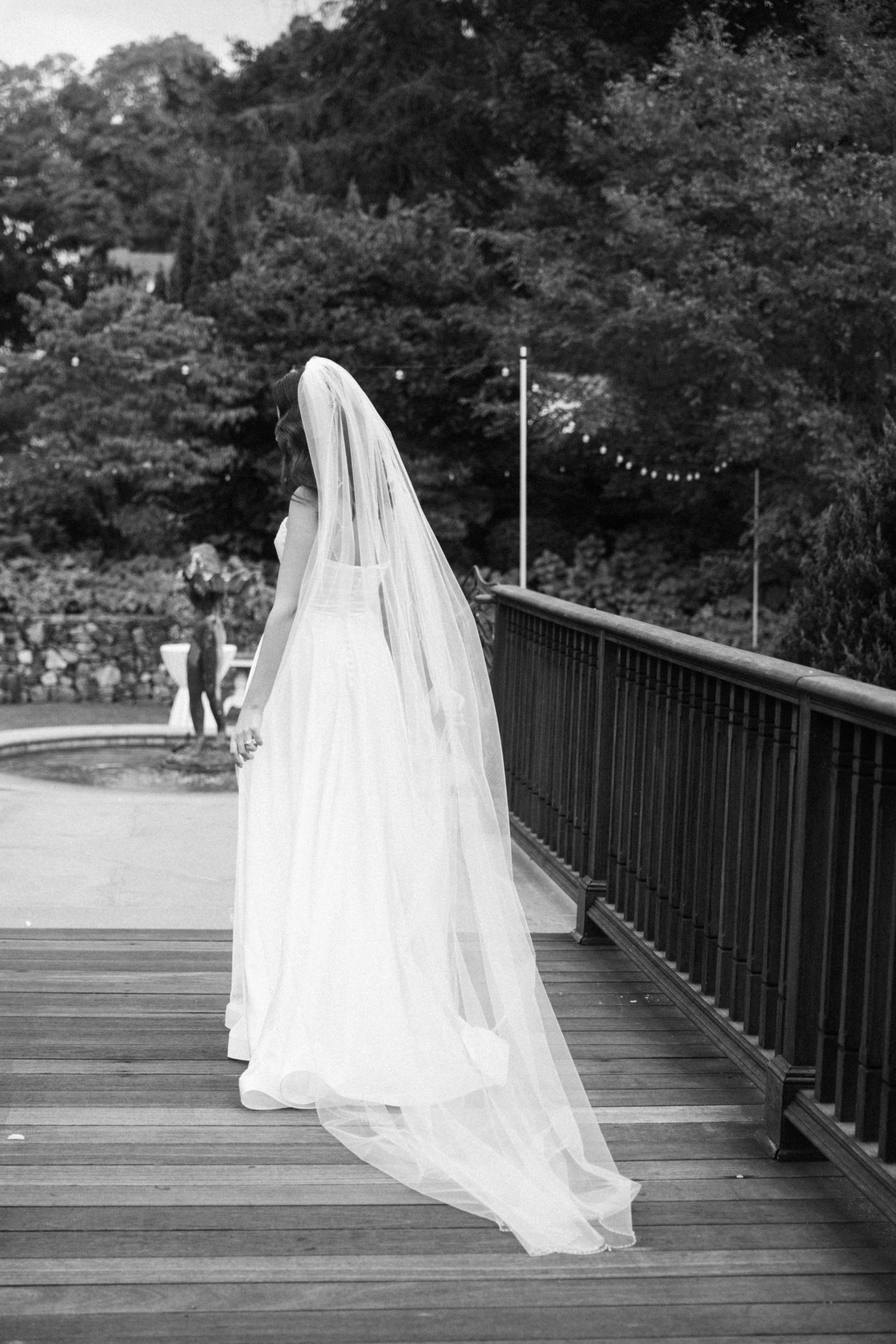 Ethereal black and white photo of a flowing wedding dress and veil on a wooden deck.