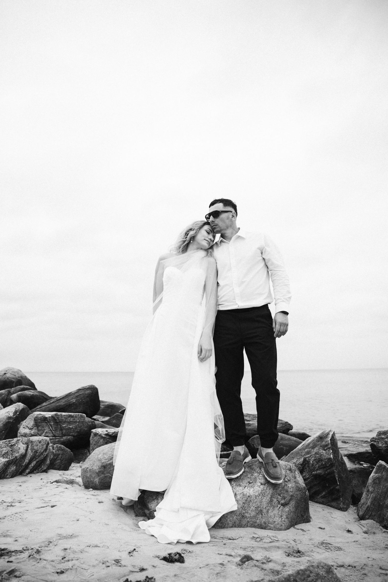 Black and white artistic wedding photos captured on rocky oceanfront.