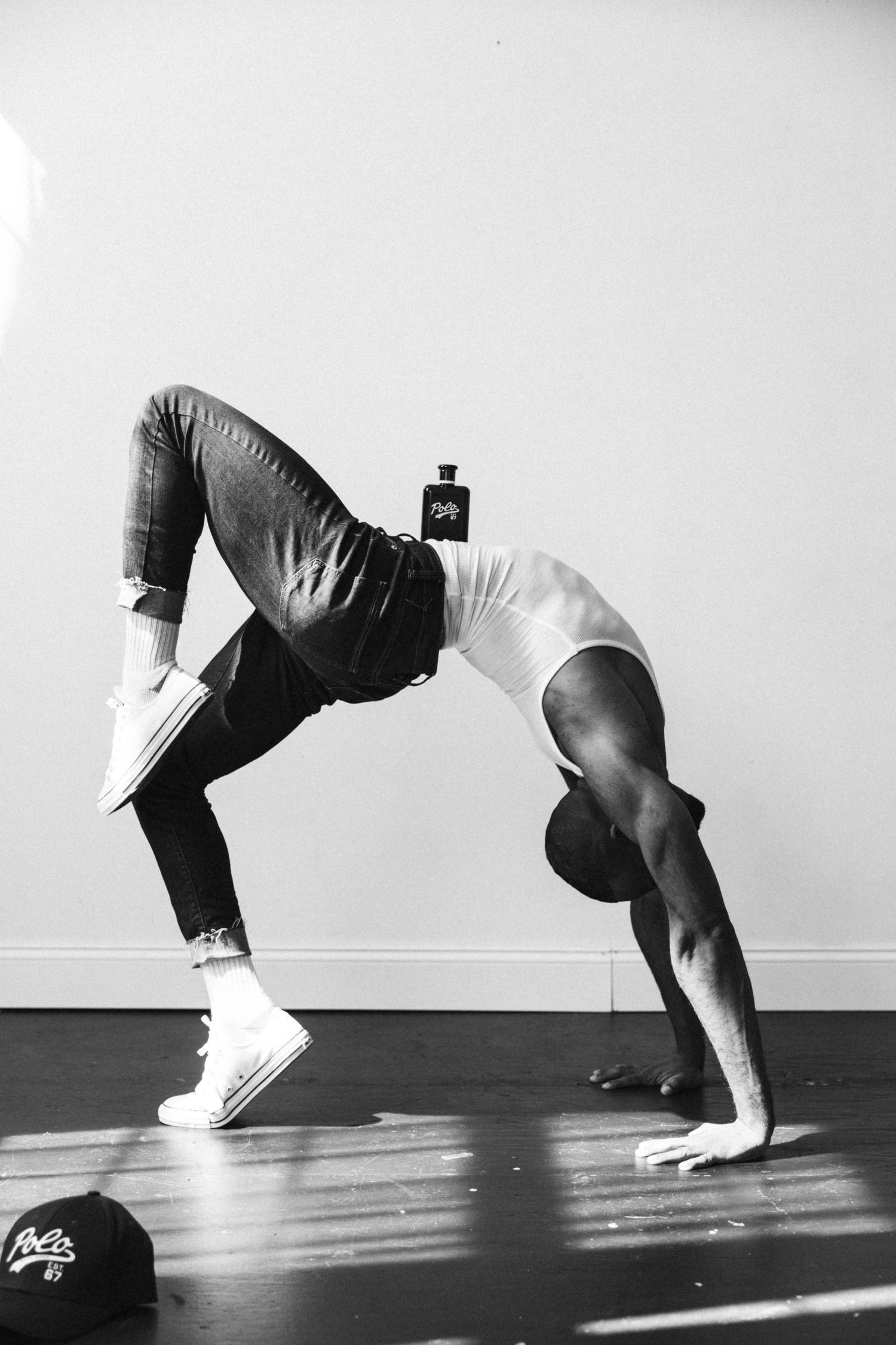 Strong athlete demonstrates backbend bridge exercise pose on hardwood floor in black and white.