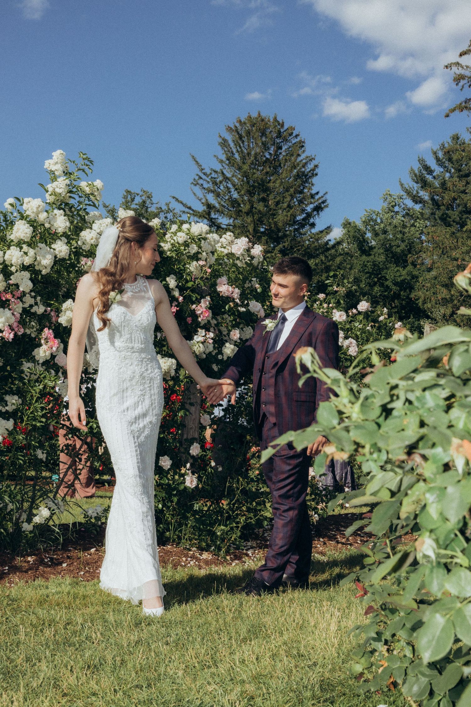 Romantic wedding photoshoot in a garden filled with roses and greenery.