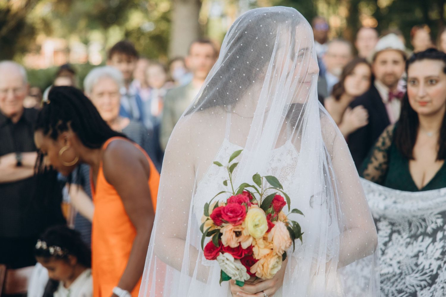 Wedding celebration with guests and floral bouquet outdoors.