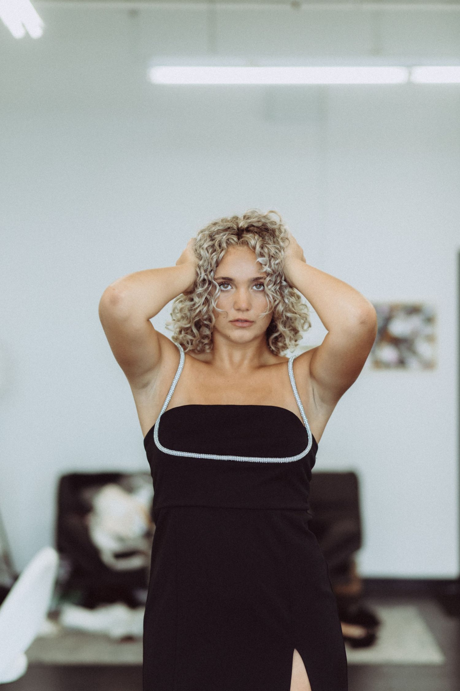 Fashion portrait series in cool tones showing off-shoulder black dress with white trim.