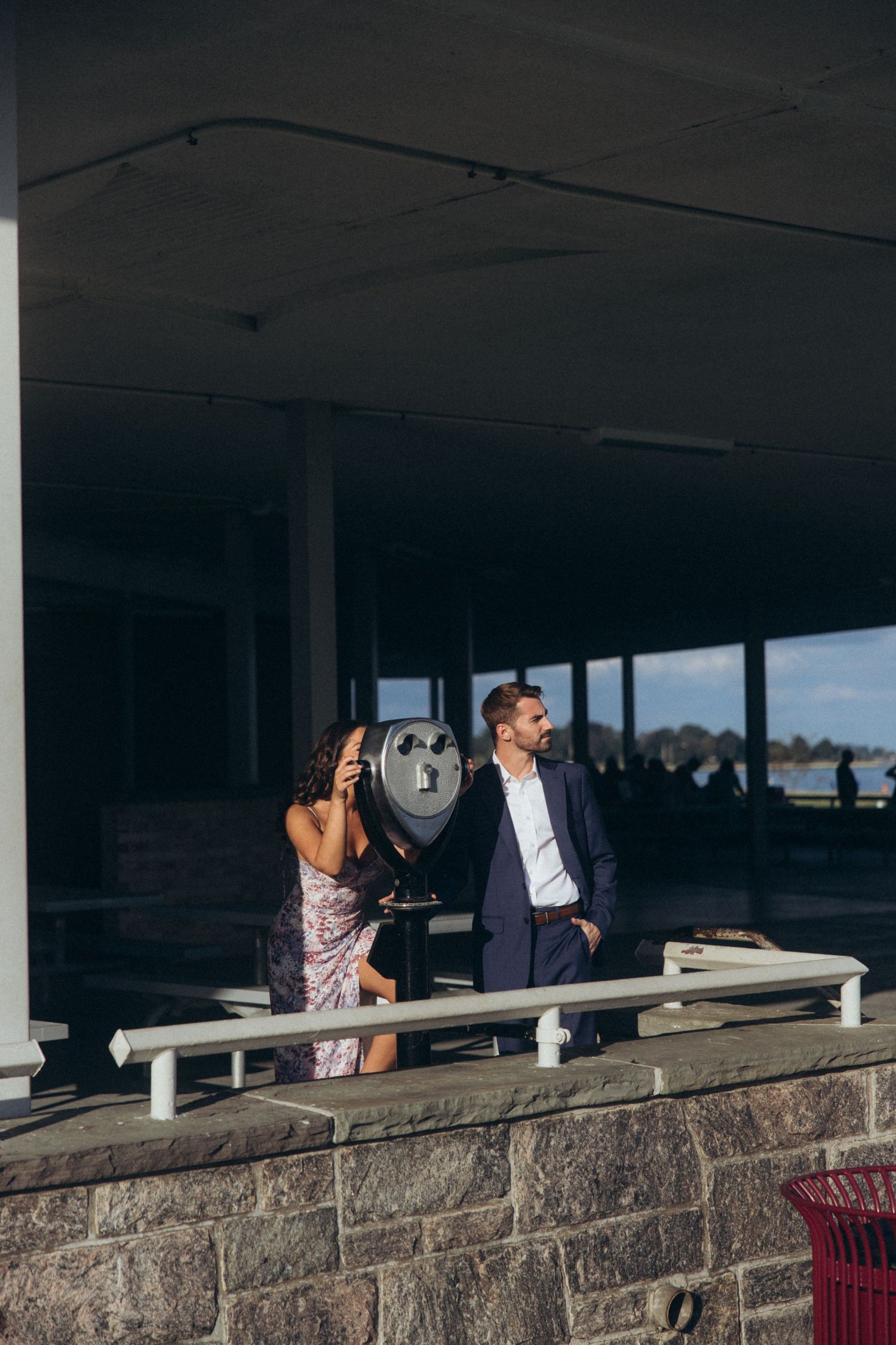 Couple sharing romantic moments along a stone wall by the water during a photo session.