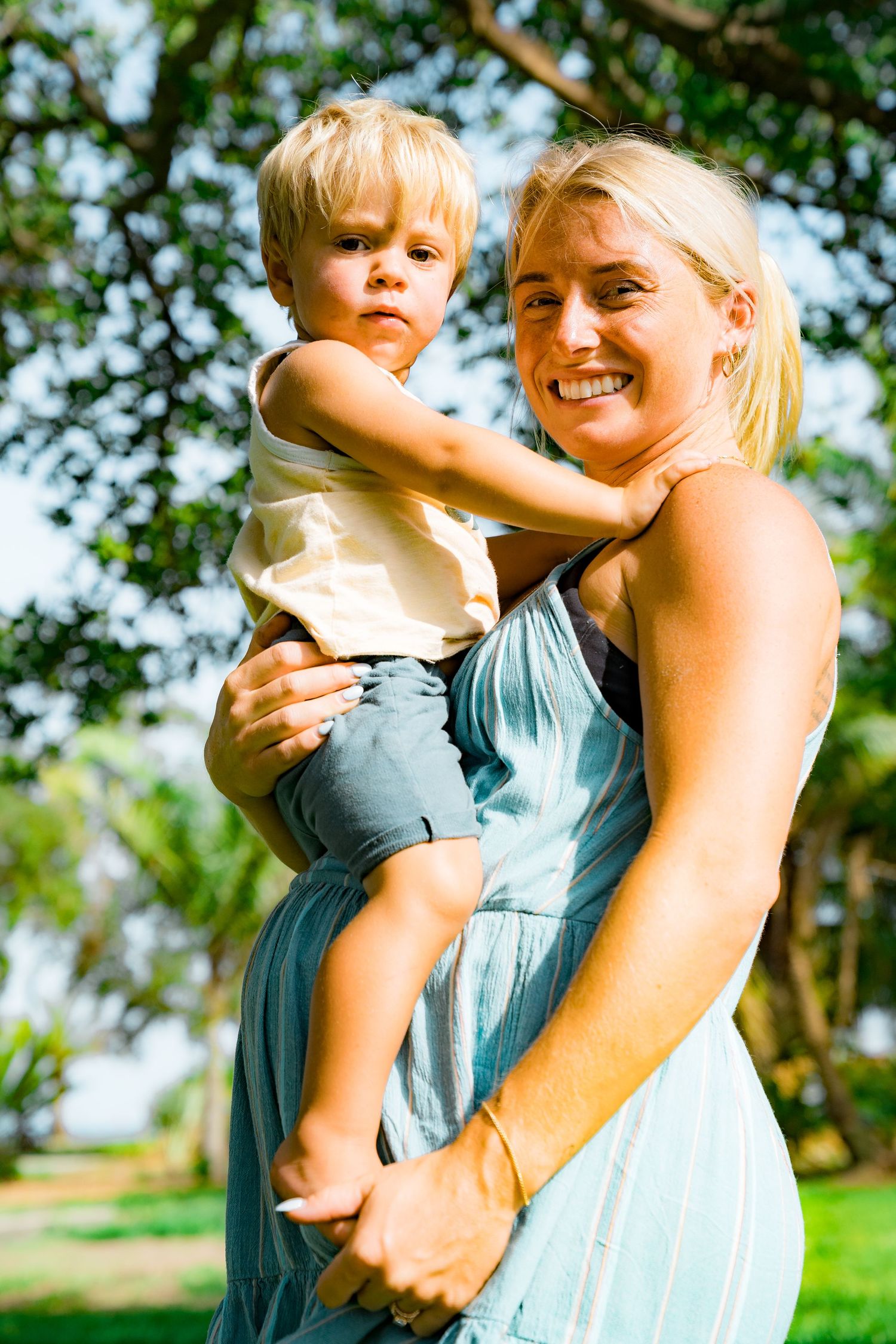 A photo of the pregnant woman with the light blue dress holding her little boy.