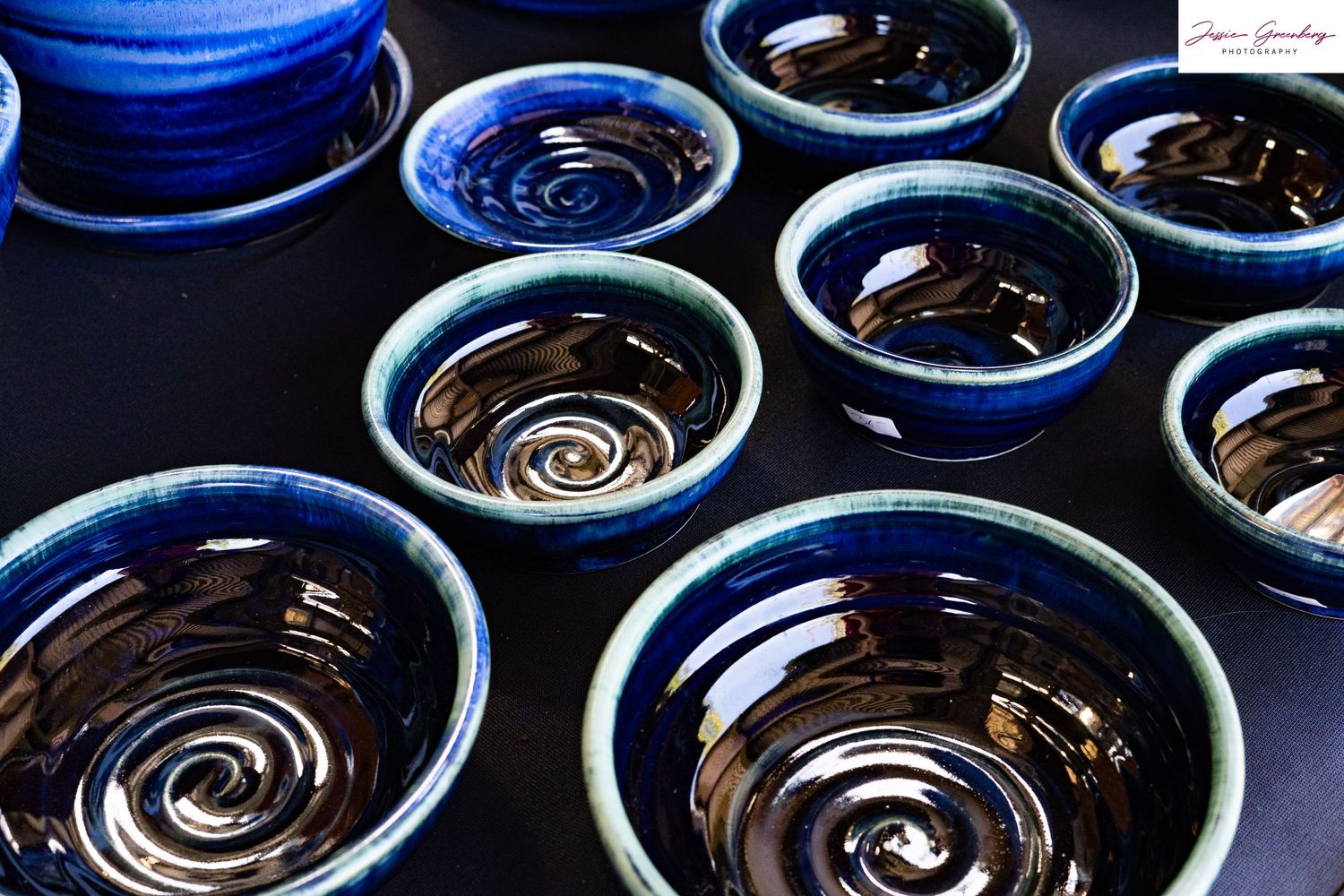 Handcrafted ceramic bowls with deep blue and black swirl glaze finish displayed on a dark surface.