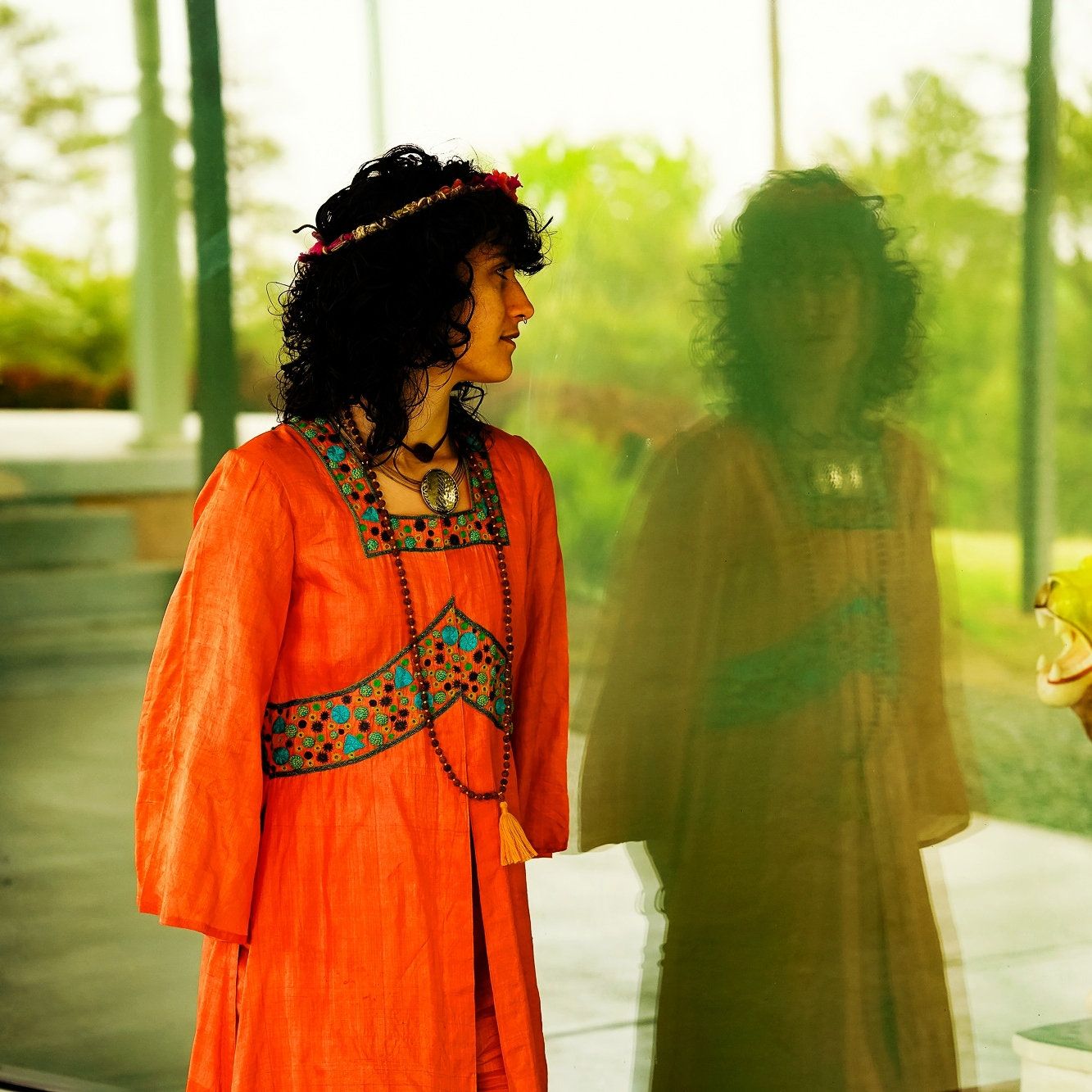a photo of a woman with curly black hair wearing a crown and an orange gown.