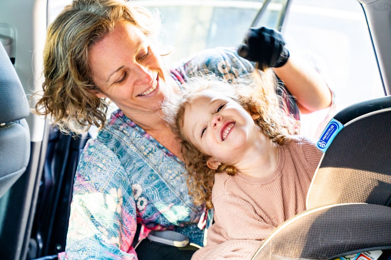 Two people sharing a joyful moment of laughter together while sitting in a car.