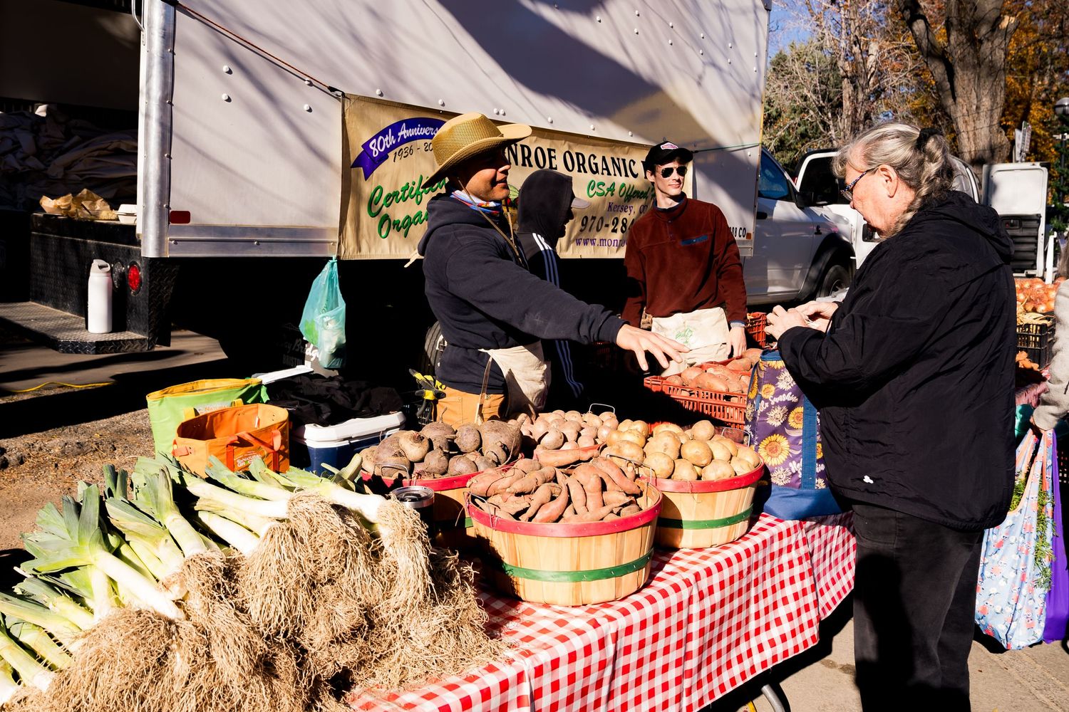 Men selling fresh potatoes at the Monroe Organic Farm booth at the farmers market.
