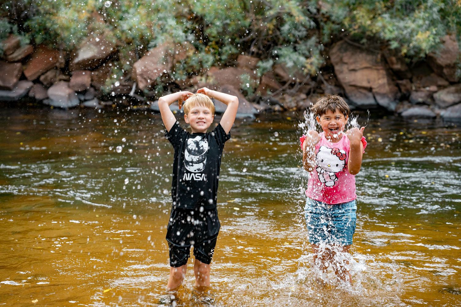 People playing and splashing in shallow water on a sunny summer day at a creek or river.