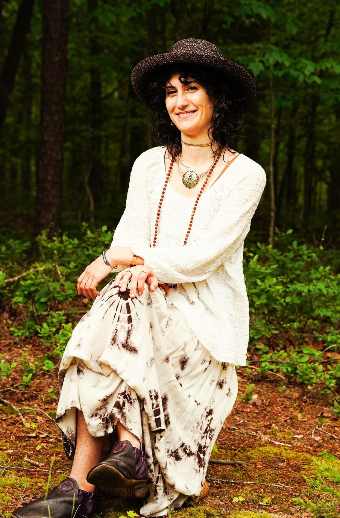 A photo of a woman with a lady sitting on the ground wearing a white top and a black hat.