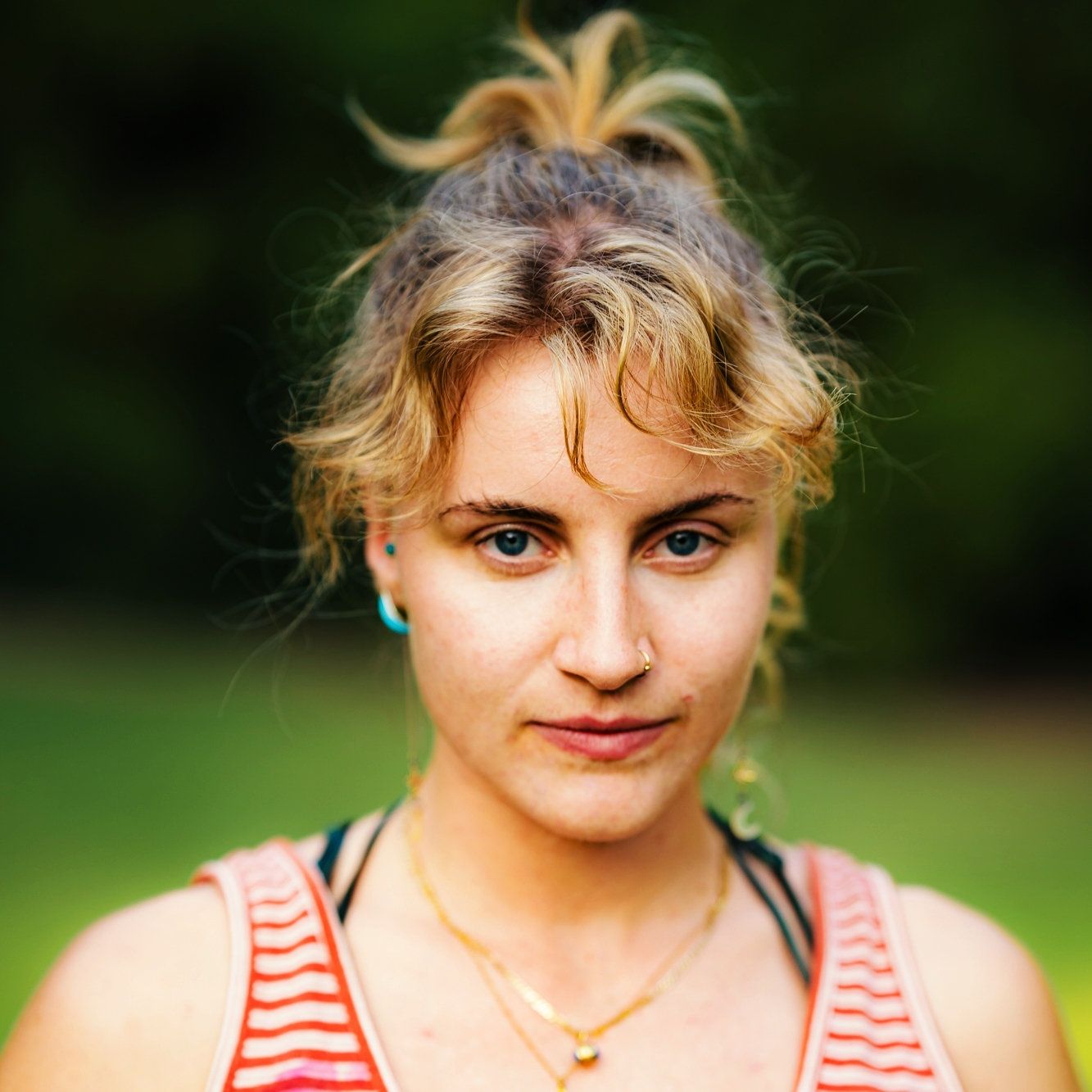 A close-up portrait series of someone wearing a red and white striped tank top in an outdoor setting with greenery.