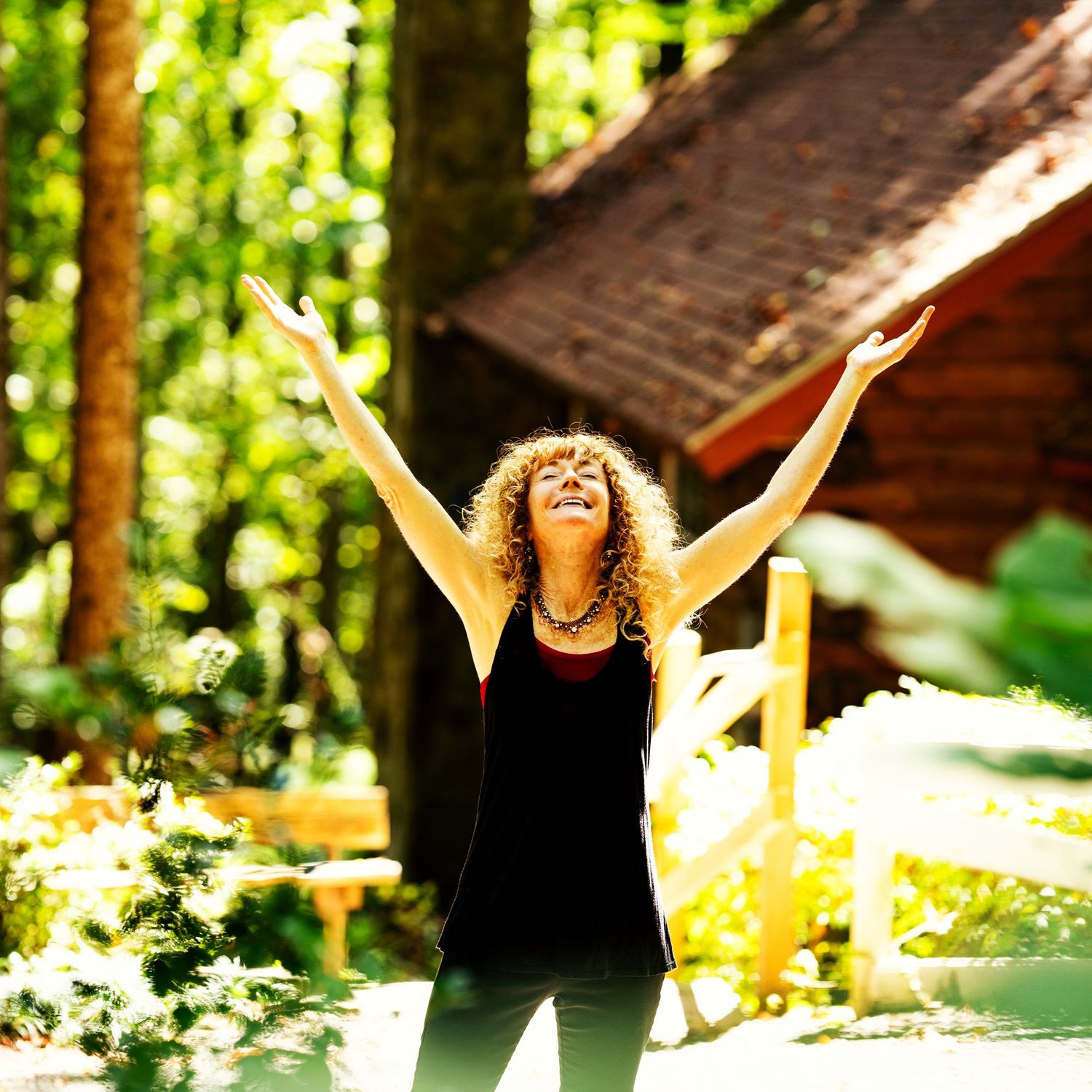 A red head woman smiling with her hands up facing the sky.