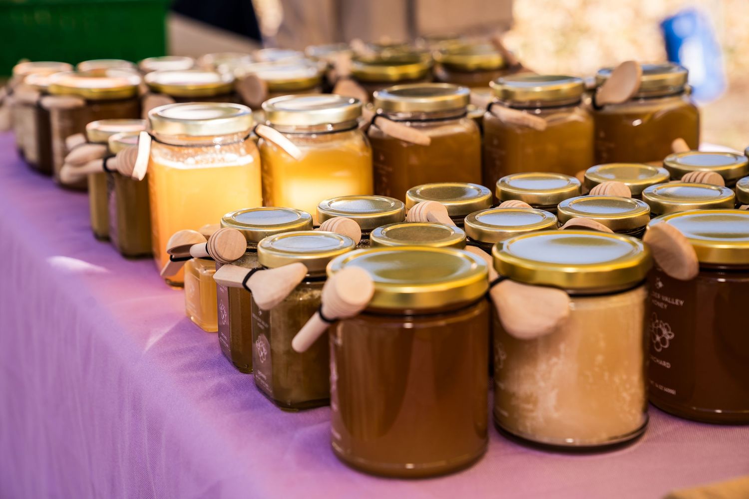 Jars of golden Happy Bees honey displayed at Boulder Farmers Market, showcasing local Colorado honey.