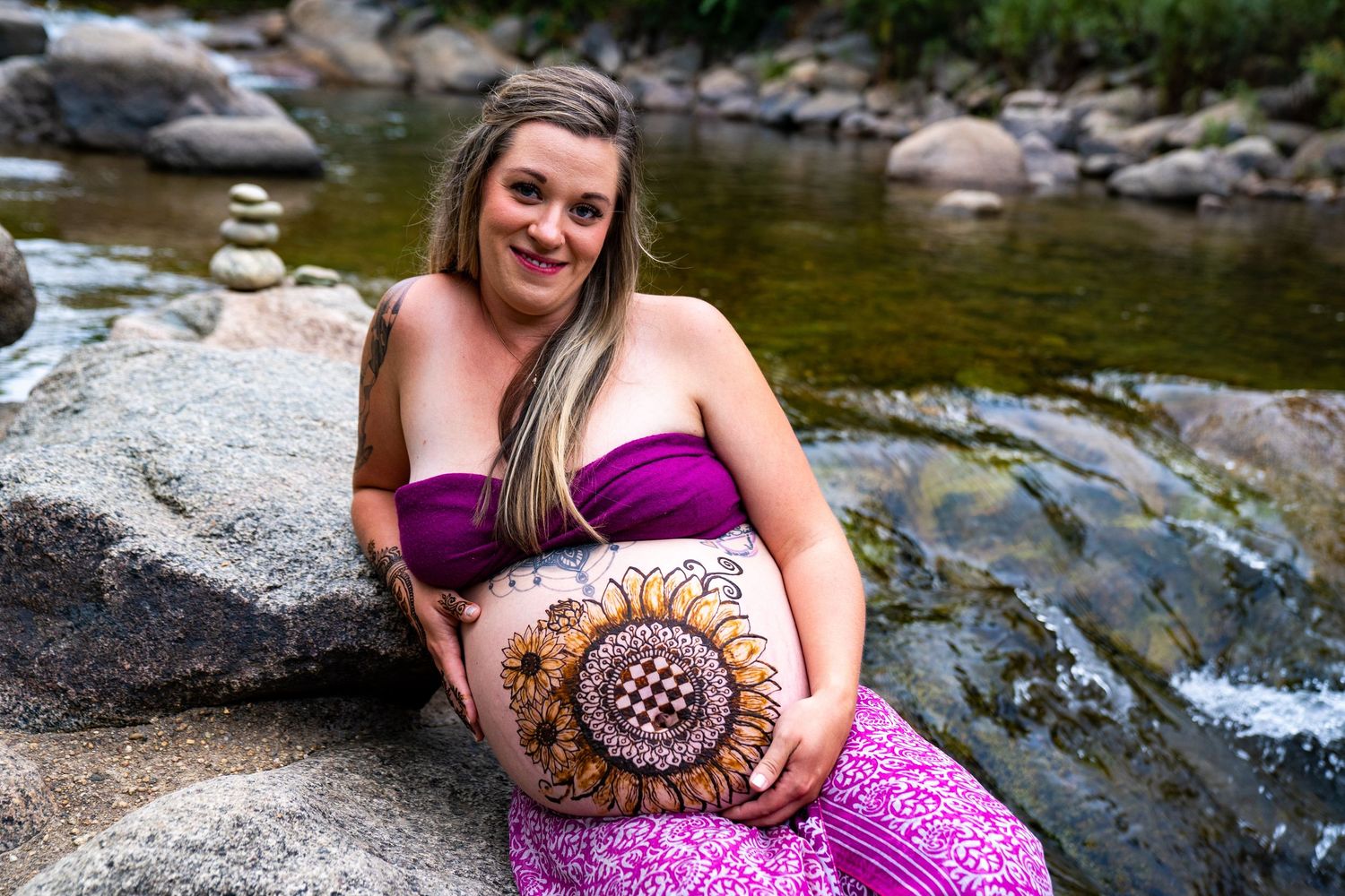 A series of outdoor portraits taken near a rocky stream with someone in a purple dress sitting on boulders in natural lighting.