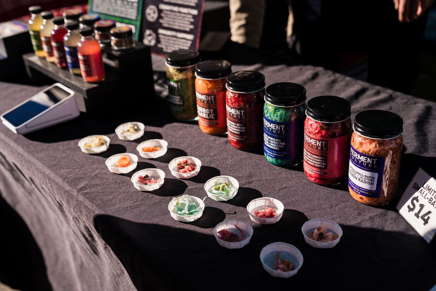 Colorful jars of fermented foods including kimchi and sauerkraut displayed at Boulder Farmers Market, locally made by Ferment Culture.