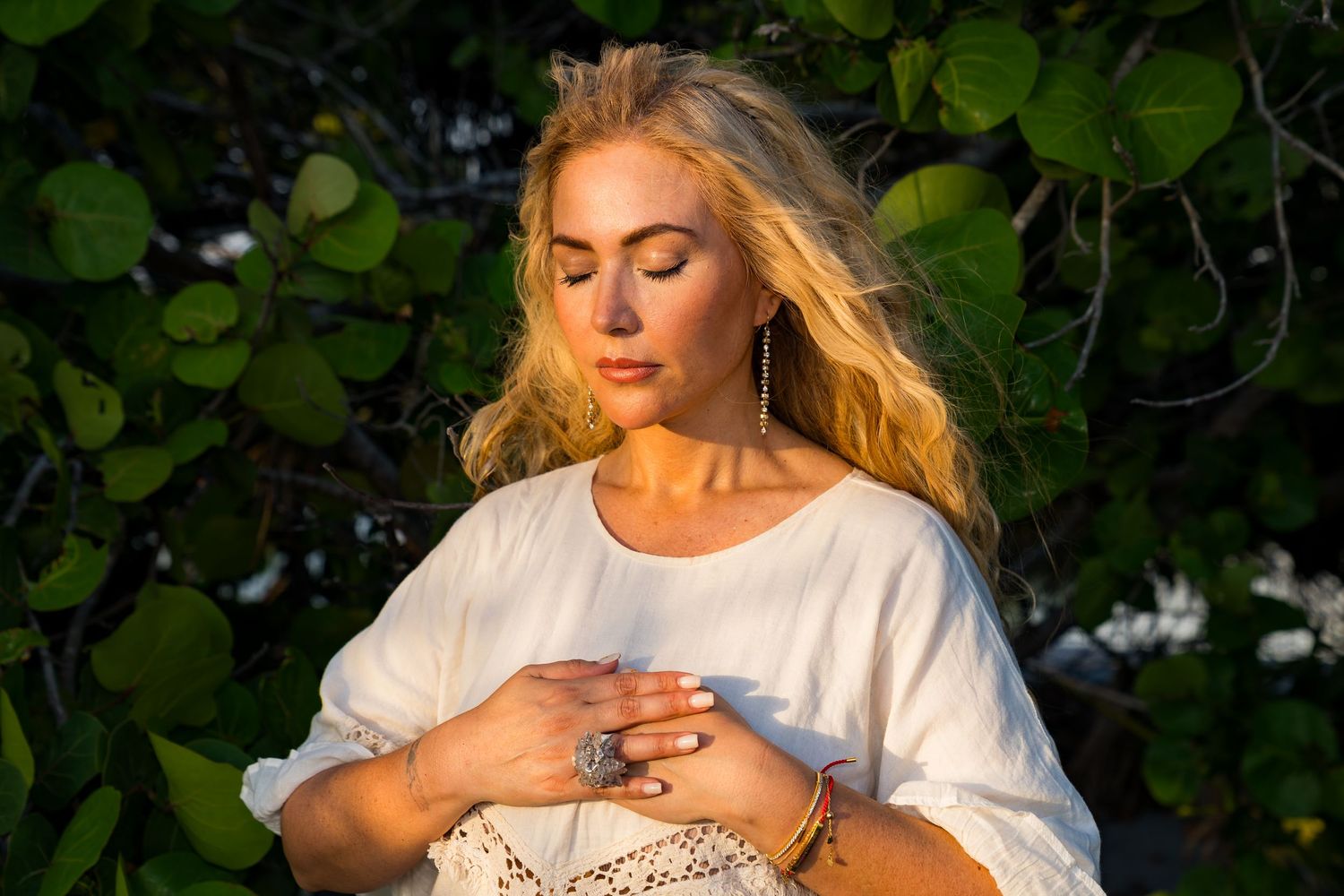 Woman in white dress poses gracefully against lush green foliage background in a series of artistic portraits.