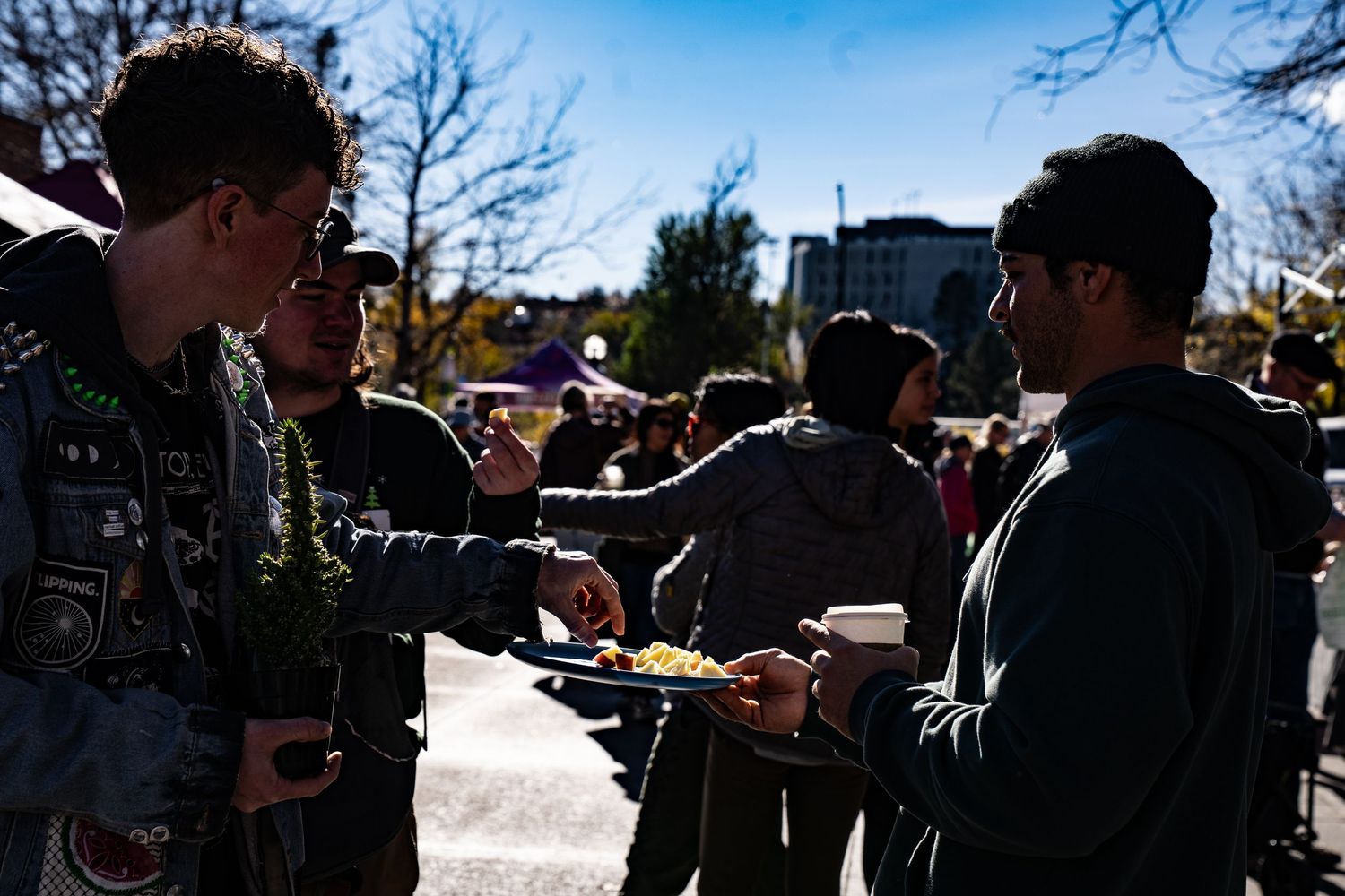 Man tasting a fresh apple sample at Boulder Farmers Market, enjoying locally grown Colorado produce.