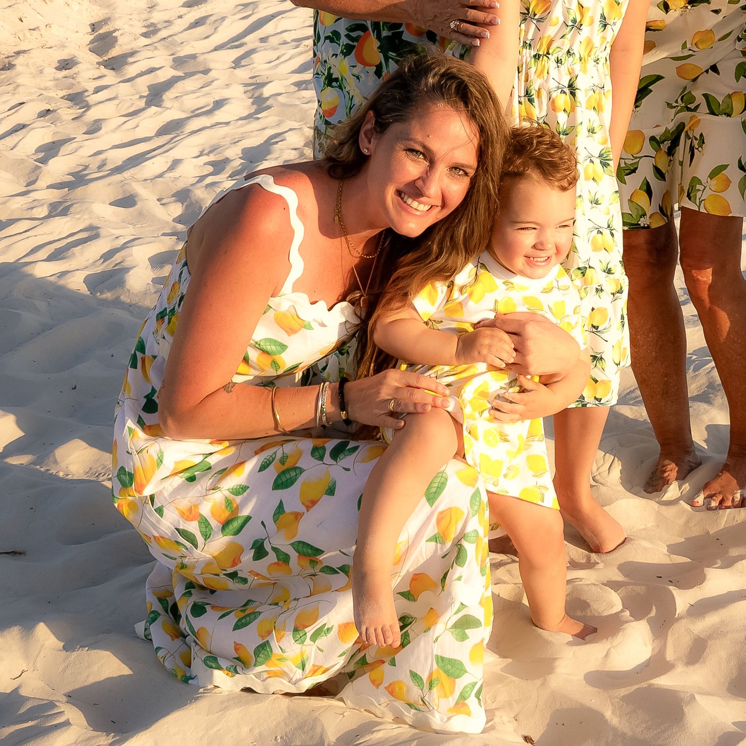 A photo of a woman and little girl in the sand with matching dresses.