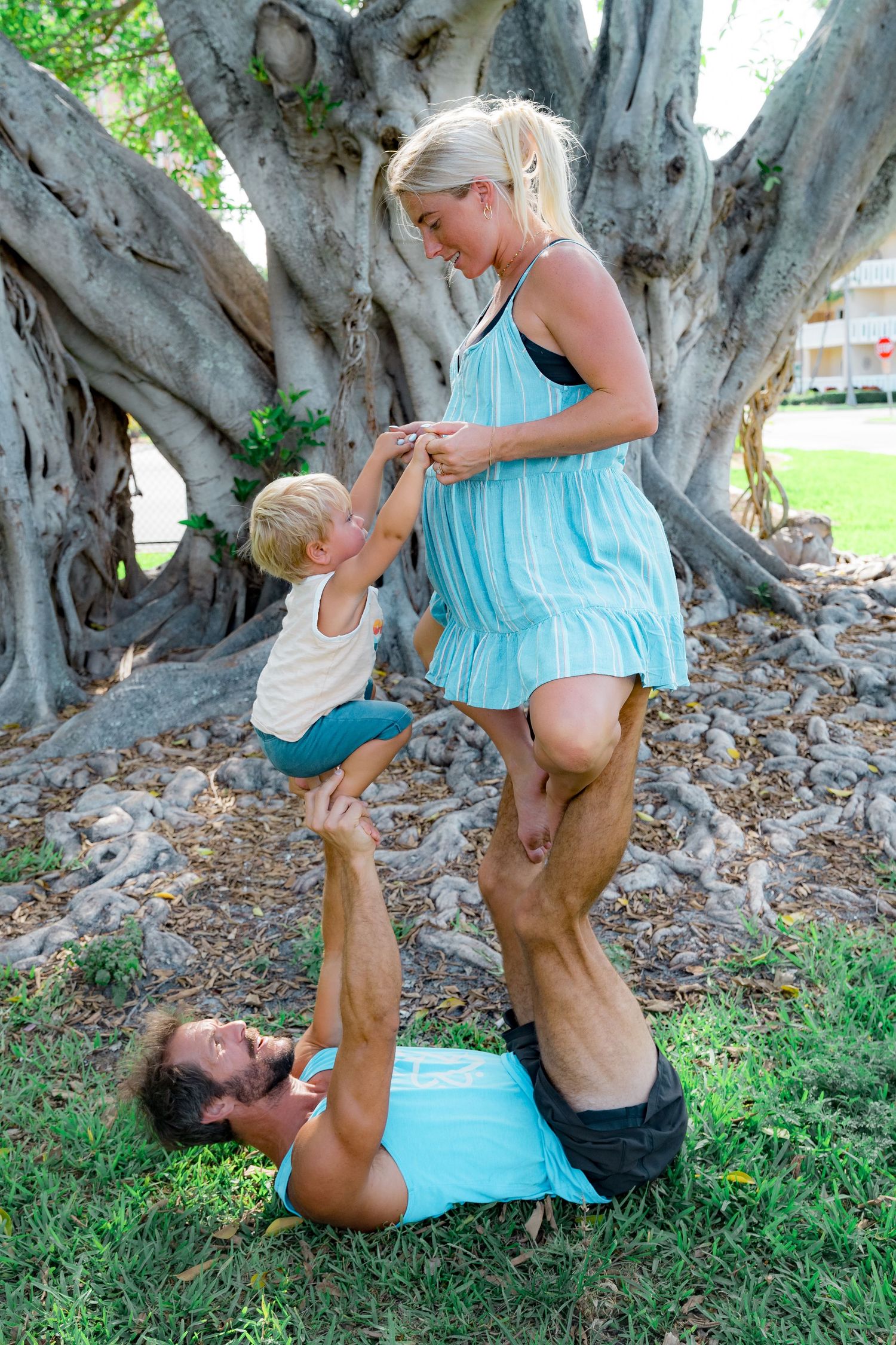 A photo of the woman holding hands with her son sitting on the feet of her husband during acro yoga.
