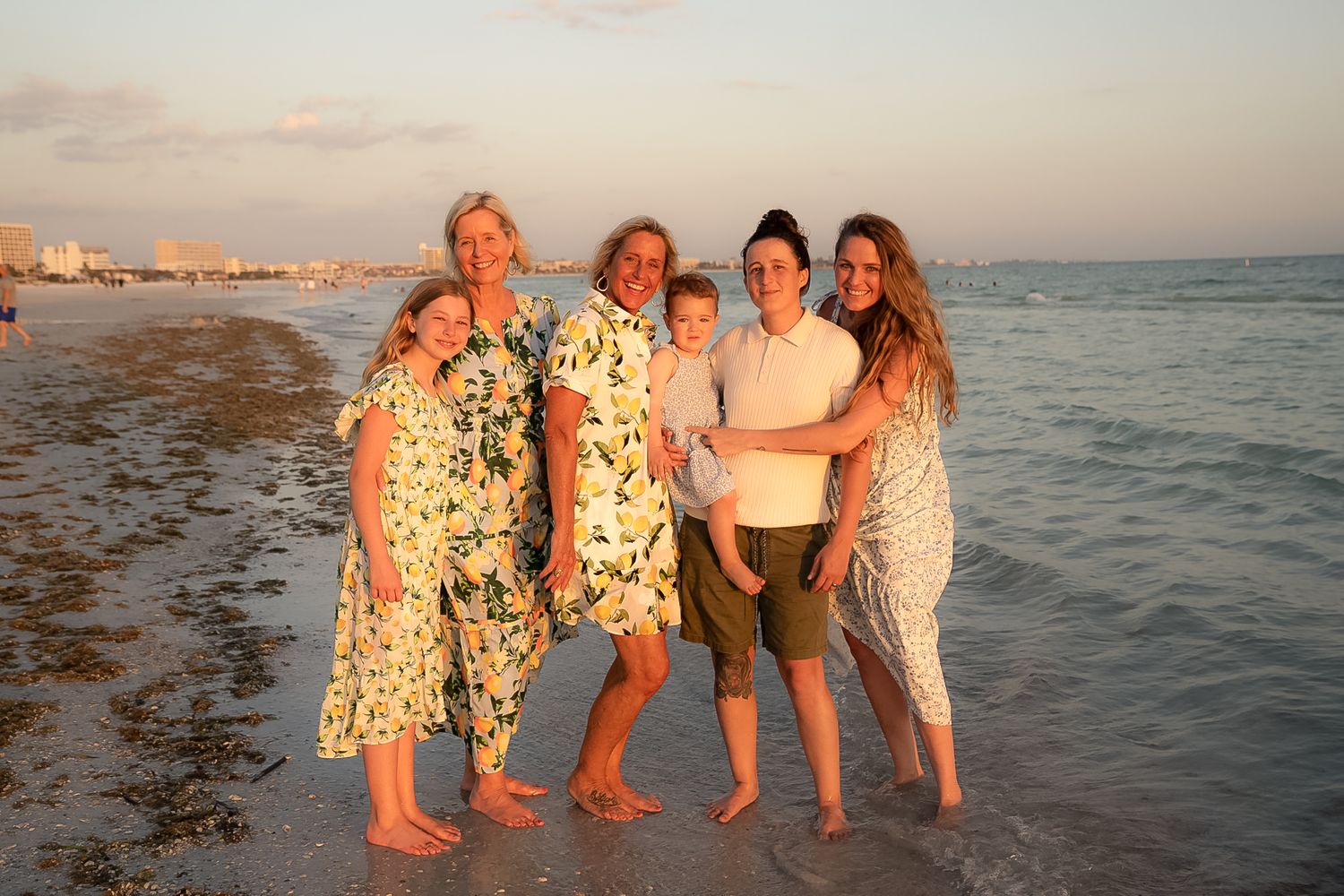A beautiful photo of a family of women with ocean behind them and beautiful sunset.