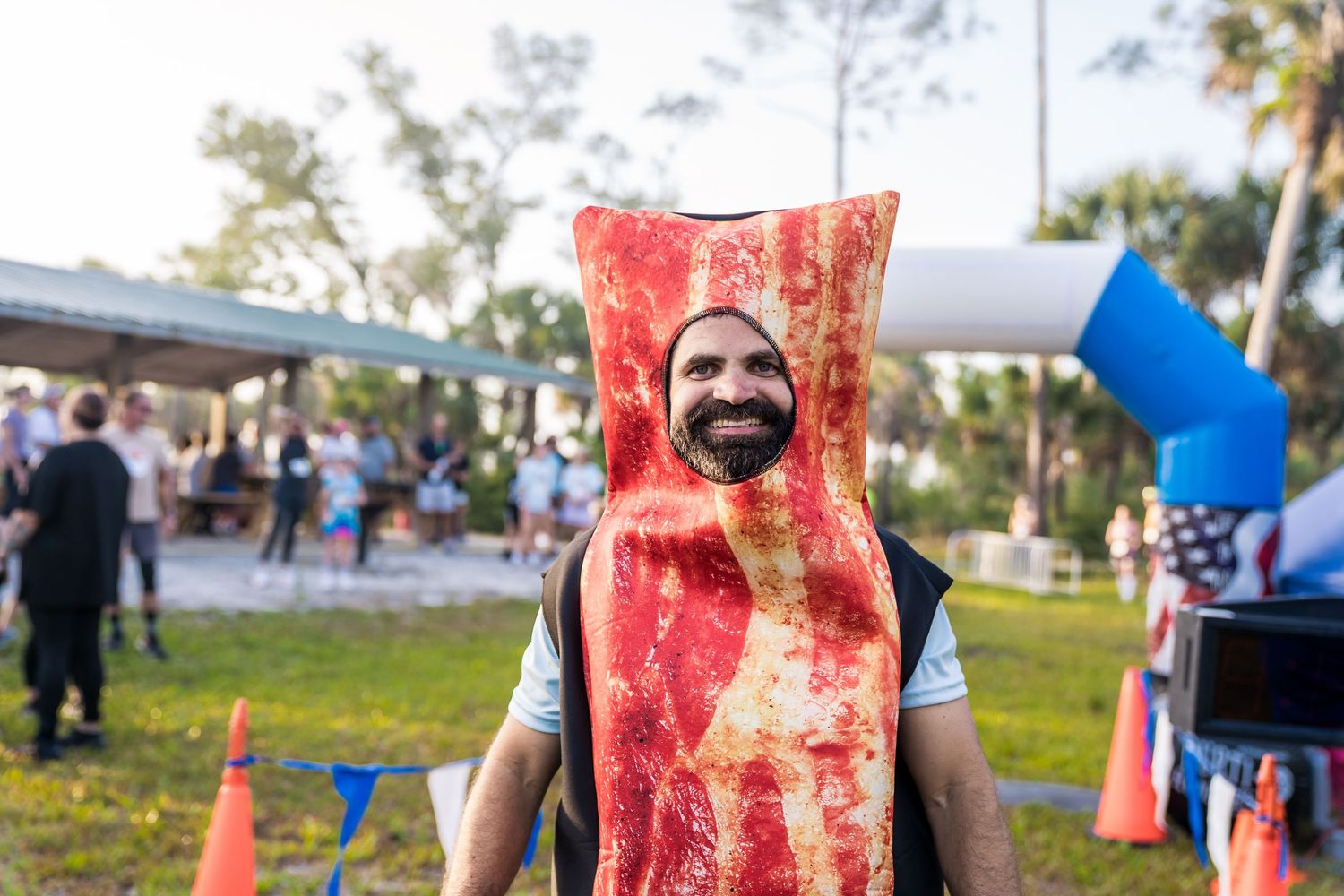 A man smiling at the camera while wearing a bacon costume.