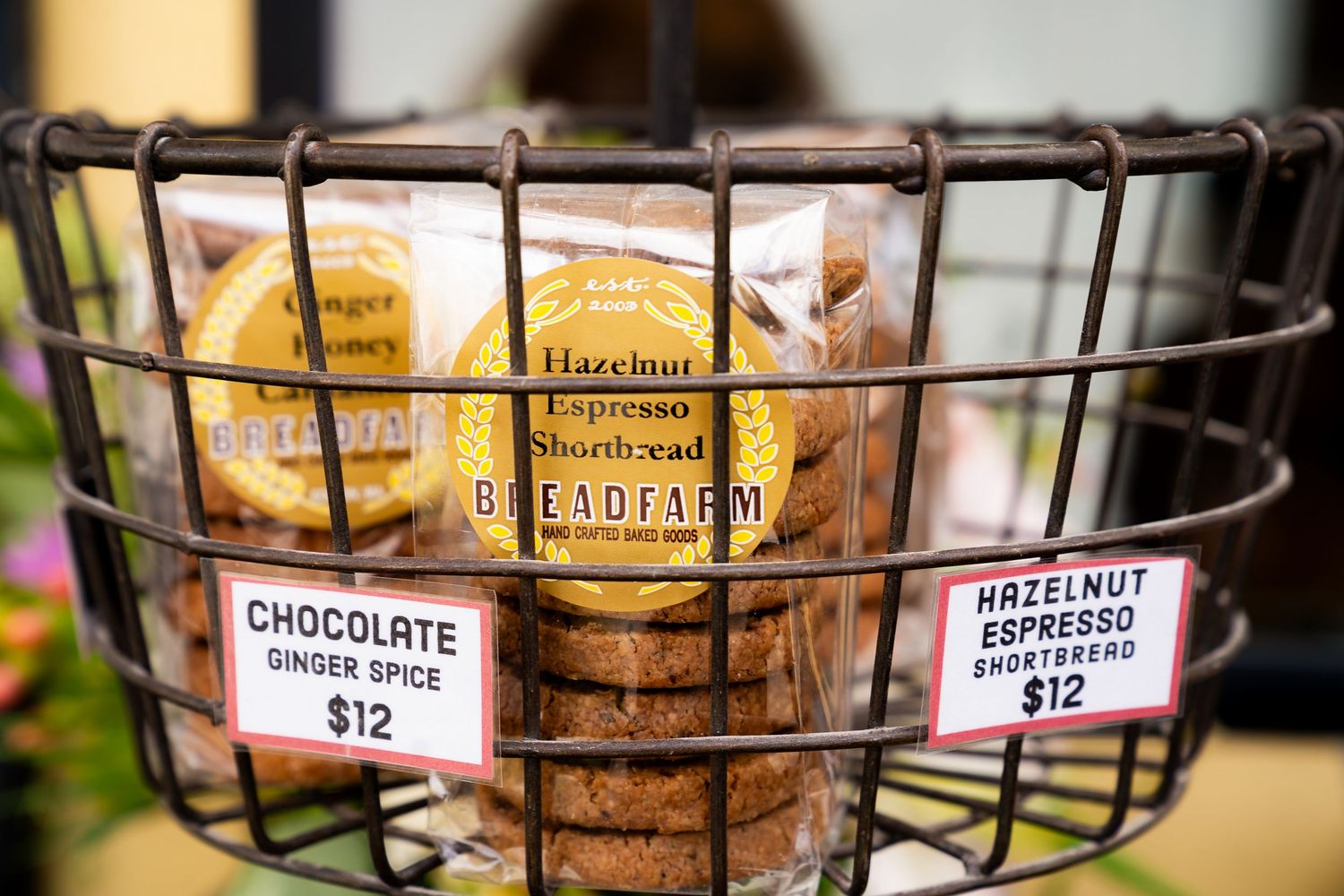 Wire basket display of Breadfarm Hazelnut Espresso Shortbread and Chocolate Ginger Spice cookies priced at $12 each.