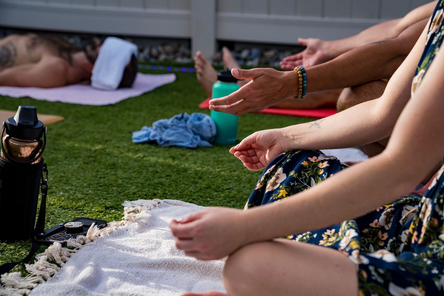 A photo of people's hands resting on their knees in meditation, opening to receive from the universe.