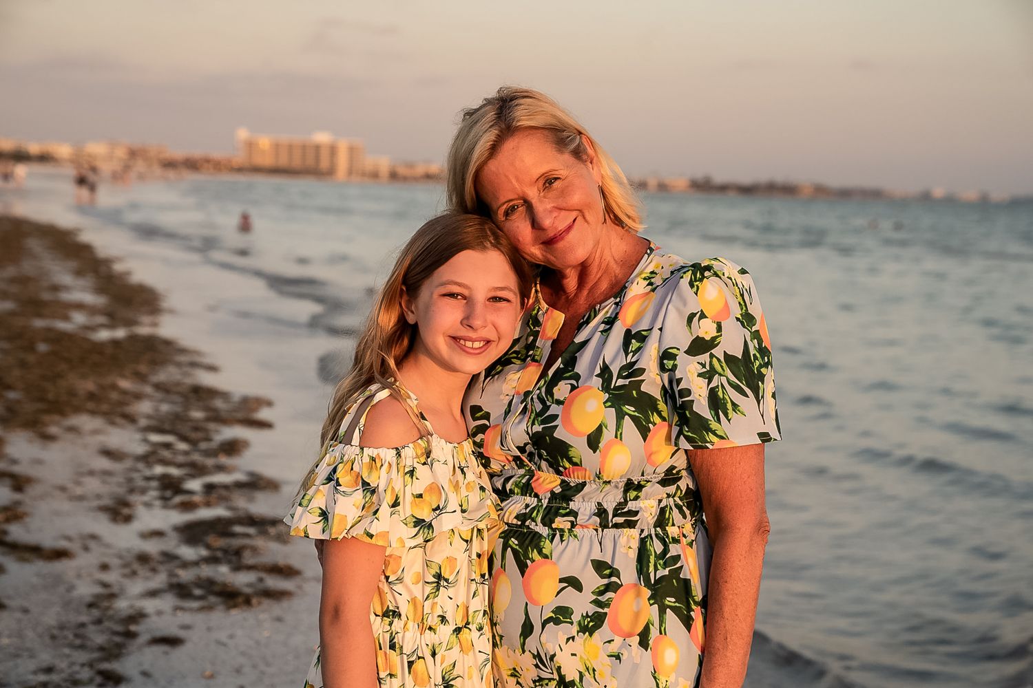 A beautiful photo of a little girl and a beautiful mother, they are both wearing patterned dresses with a sunset.