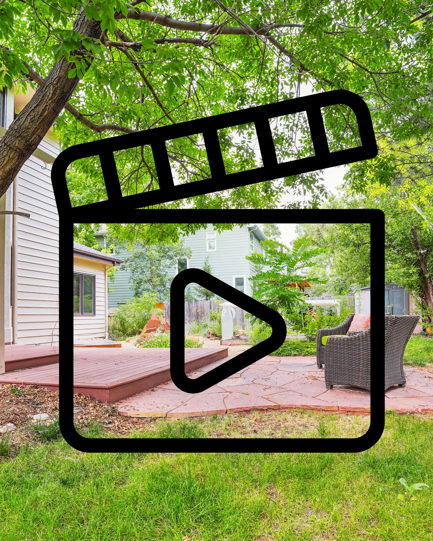 Outdoor patio with red flagstone, wood deck, wicker furniture, and lush green trees in a residential backyard.