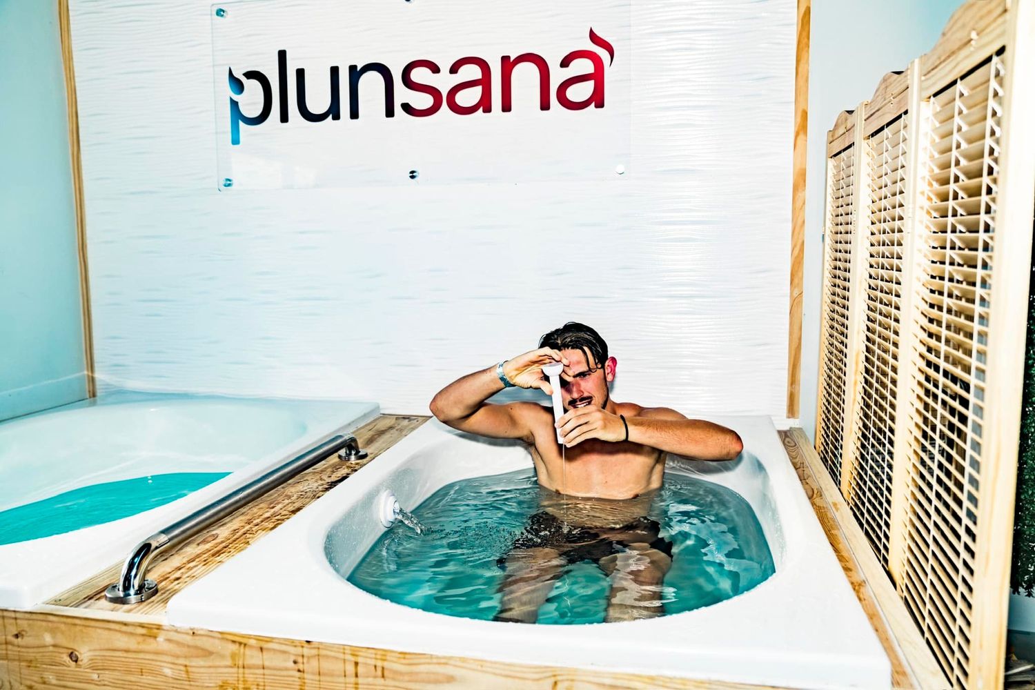 Man relaxing in a Plunsana cold plunge ice bath tub, taking a selfie while soaking in the refreshing water.