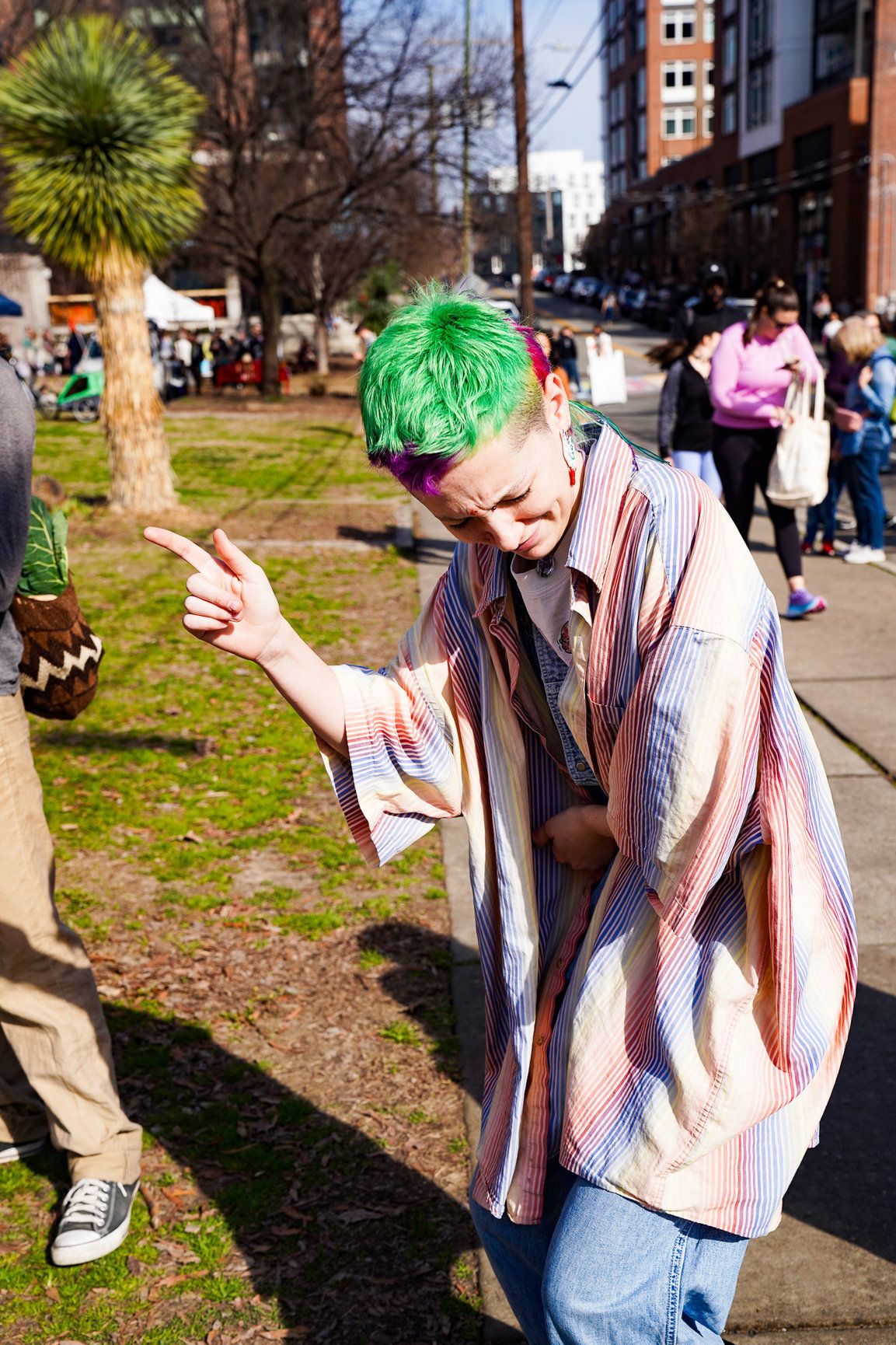 A woman with colorful hair dances joyfully in downtown Boulder, moving freely to the rhythm of the street.