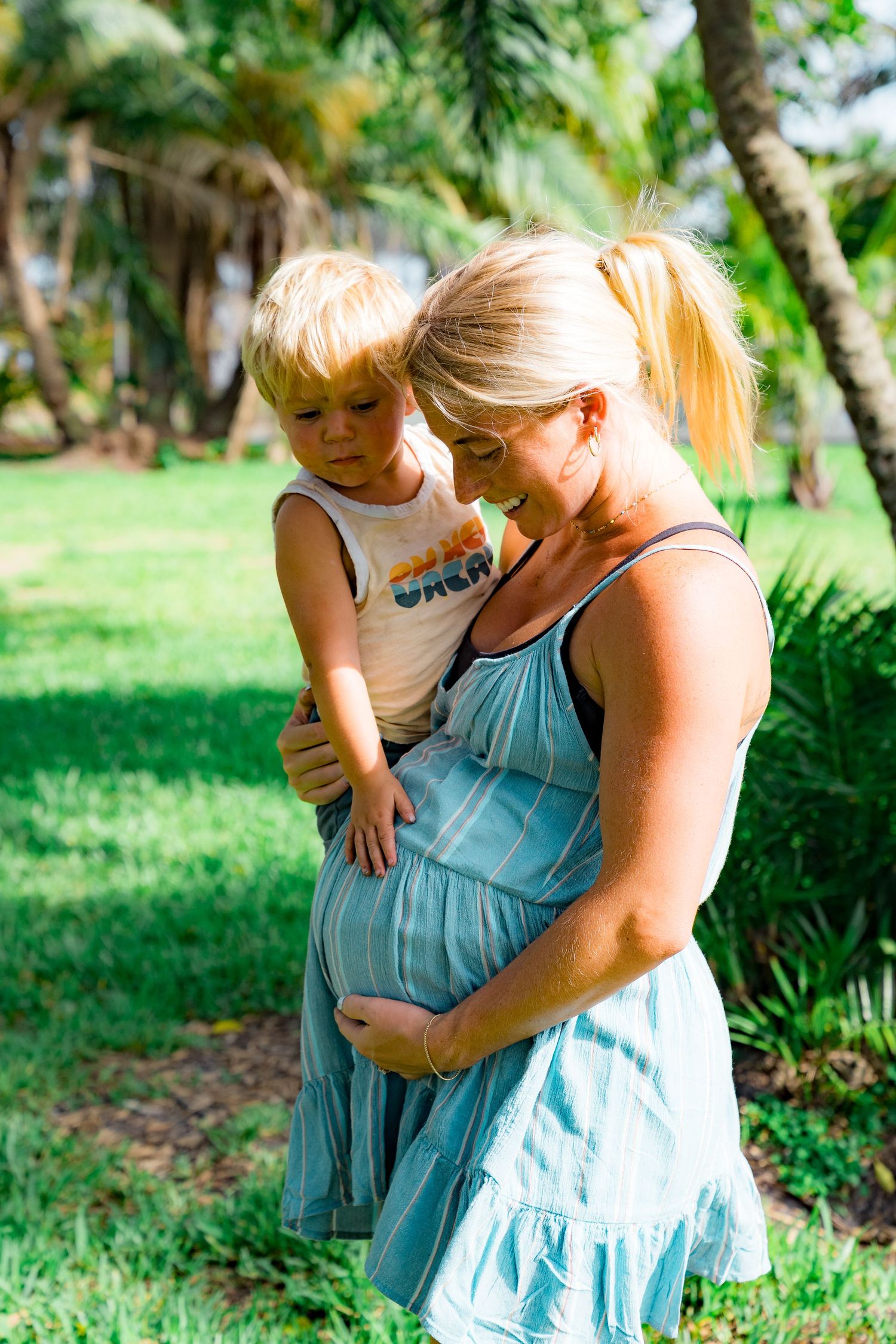 A photo of the pregnant mother holding her belly and the little boy touching her belly.
