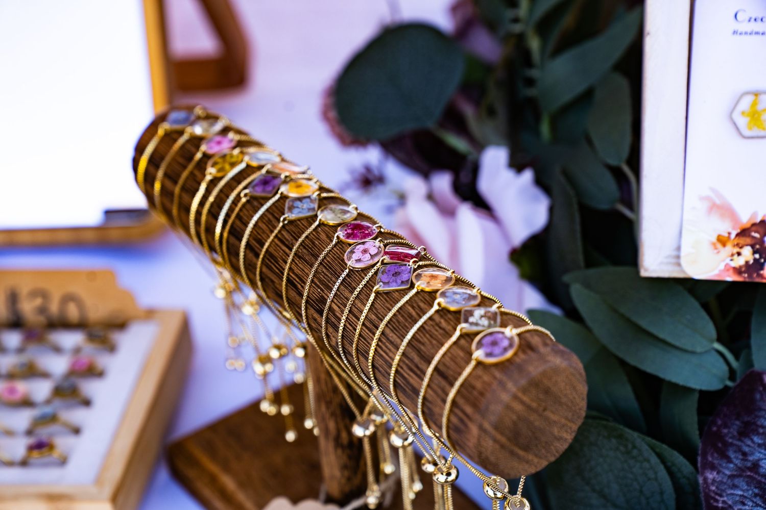 Close-up of dainty bracelets featuring hand-pressed flowers at the farmers market.