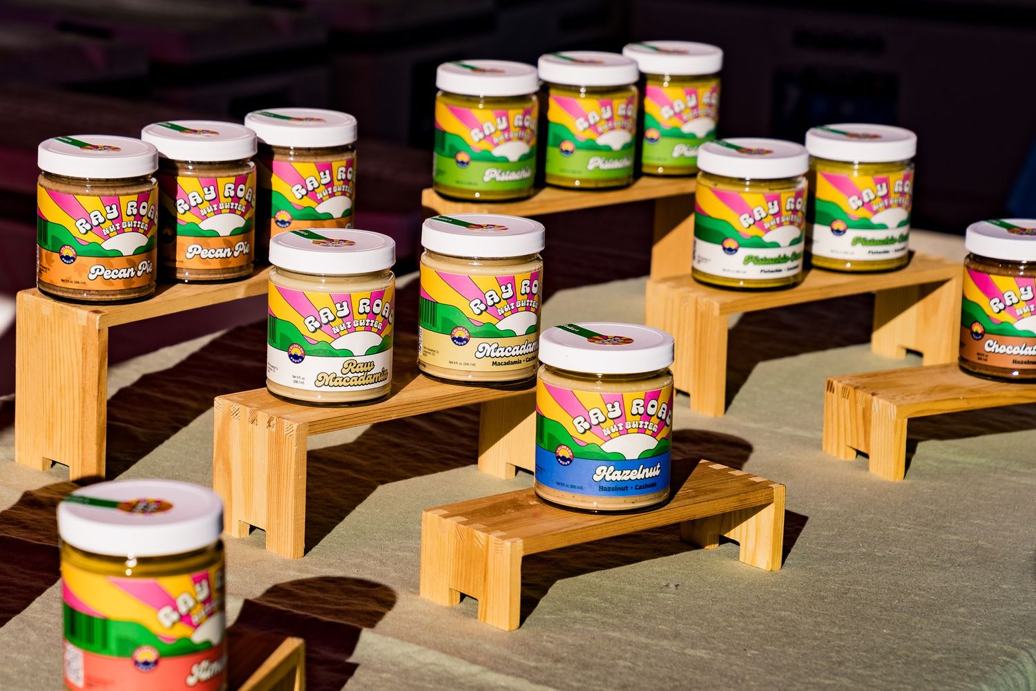 Jars of Ray Road Nut Butter glowing in the sunlight at the farmers market.