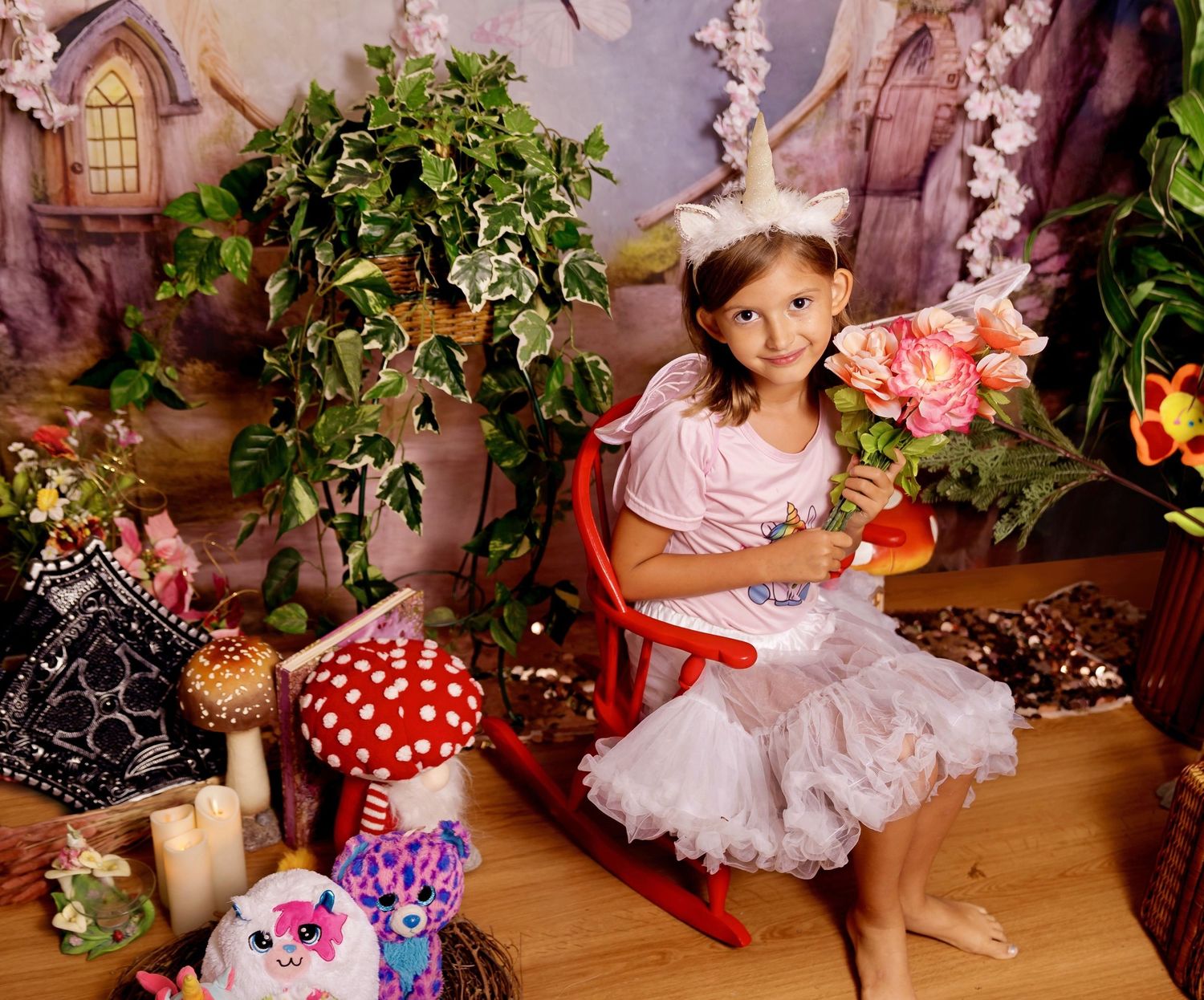 Young girl in unicorn costume with tutu holds flowers in a whimsical fairy tale photo studio setting.