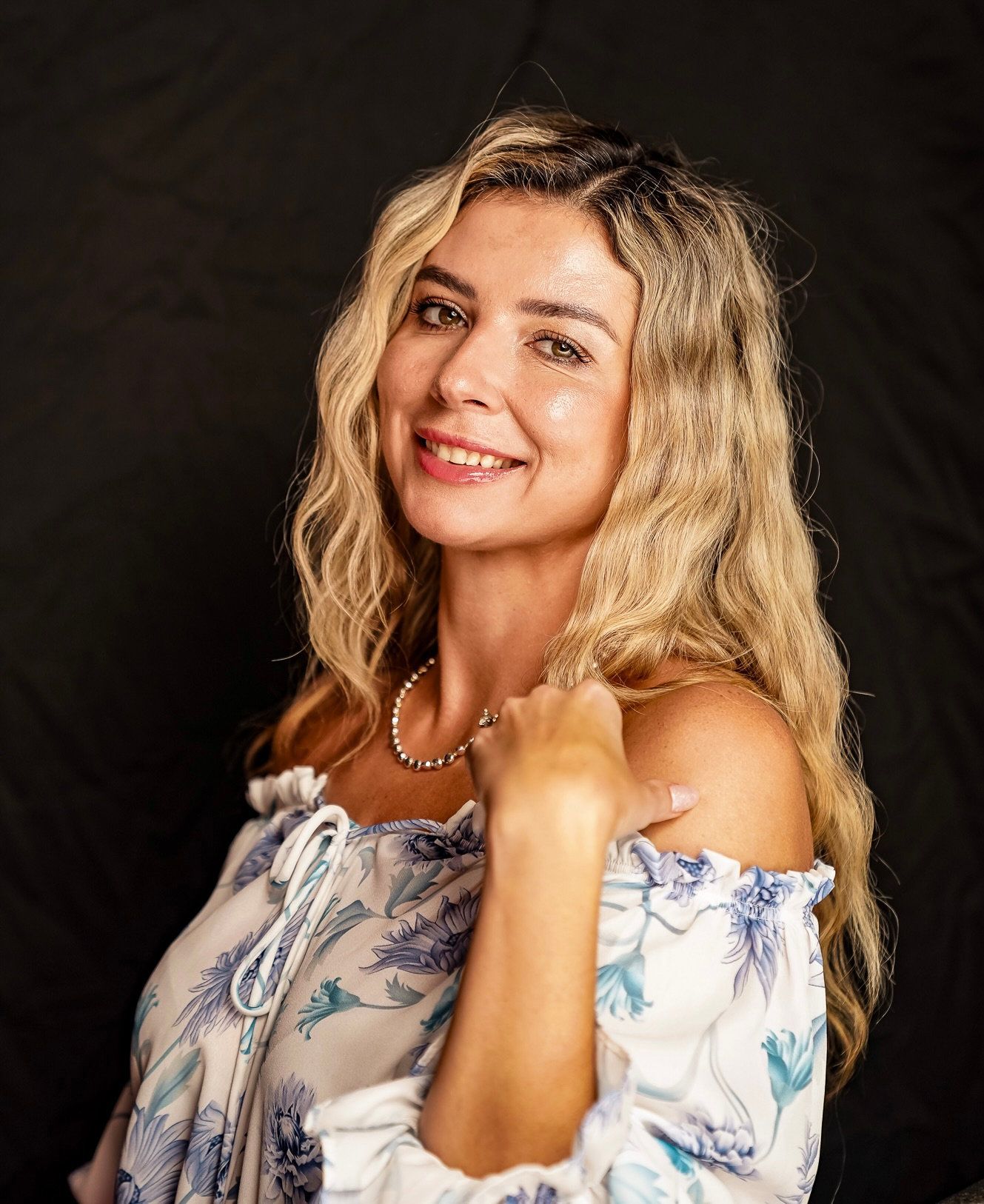 A picture of a blonde woman looking at the camera and smiling with a black backdrop.