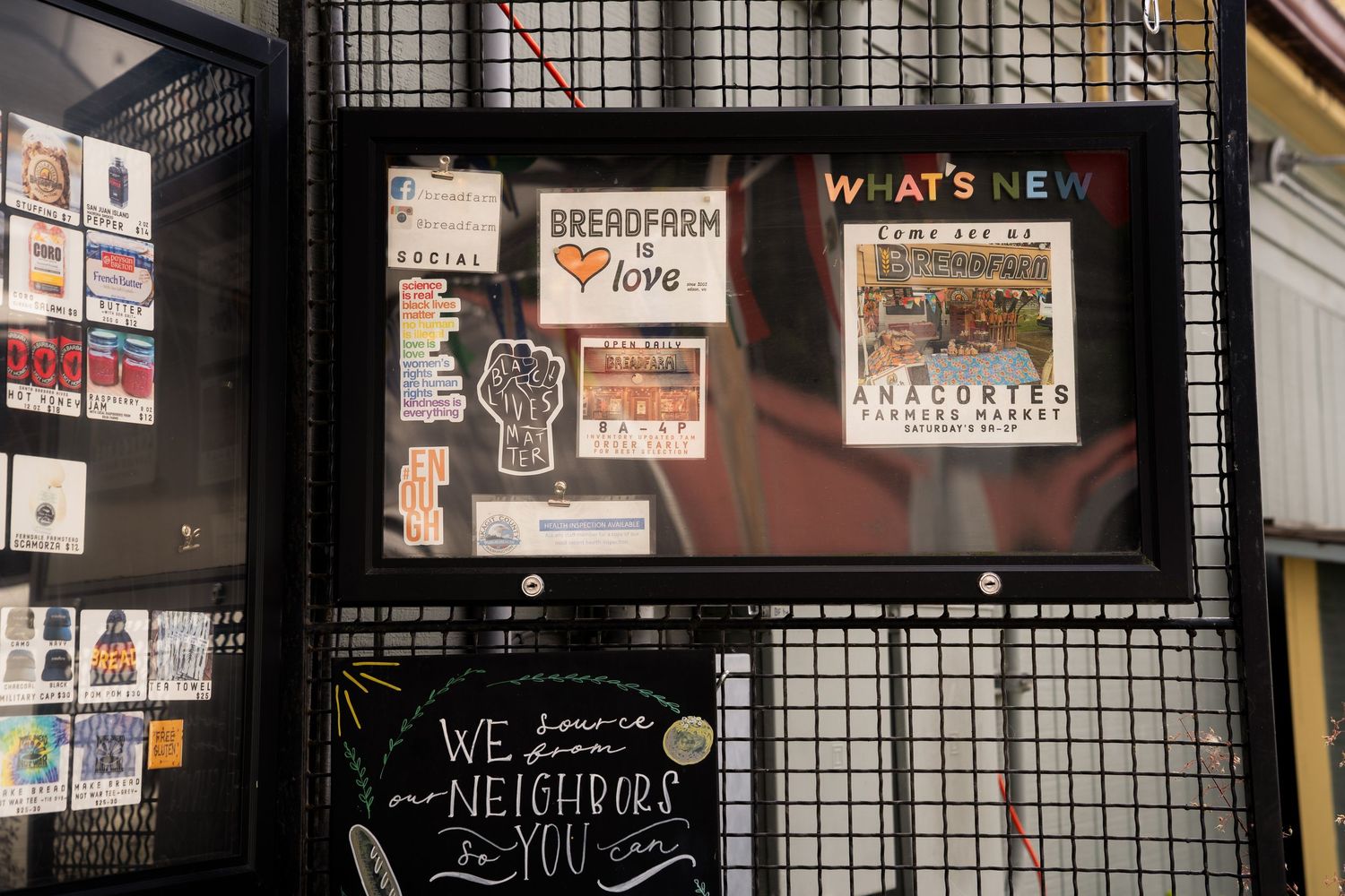 A bulletin board displaying Breadfarm and Anacortes Farmers Market signs with a neighborhood message below.