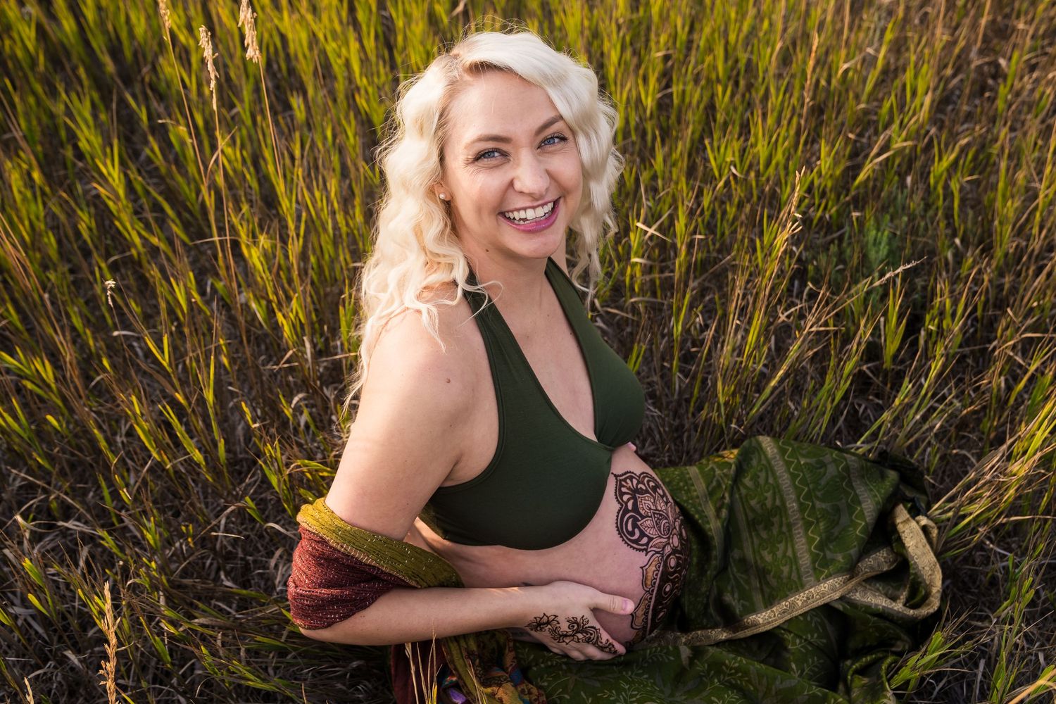 A person in a black dress poses in a golden field during sunset creating a warm and dreamy outdoor portrait.