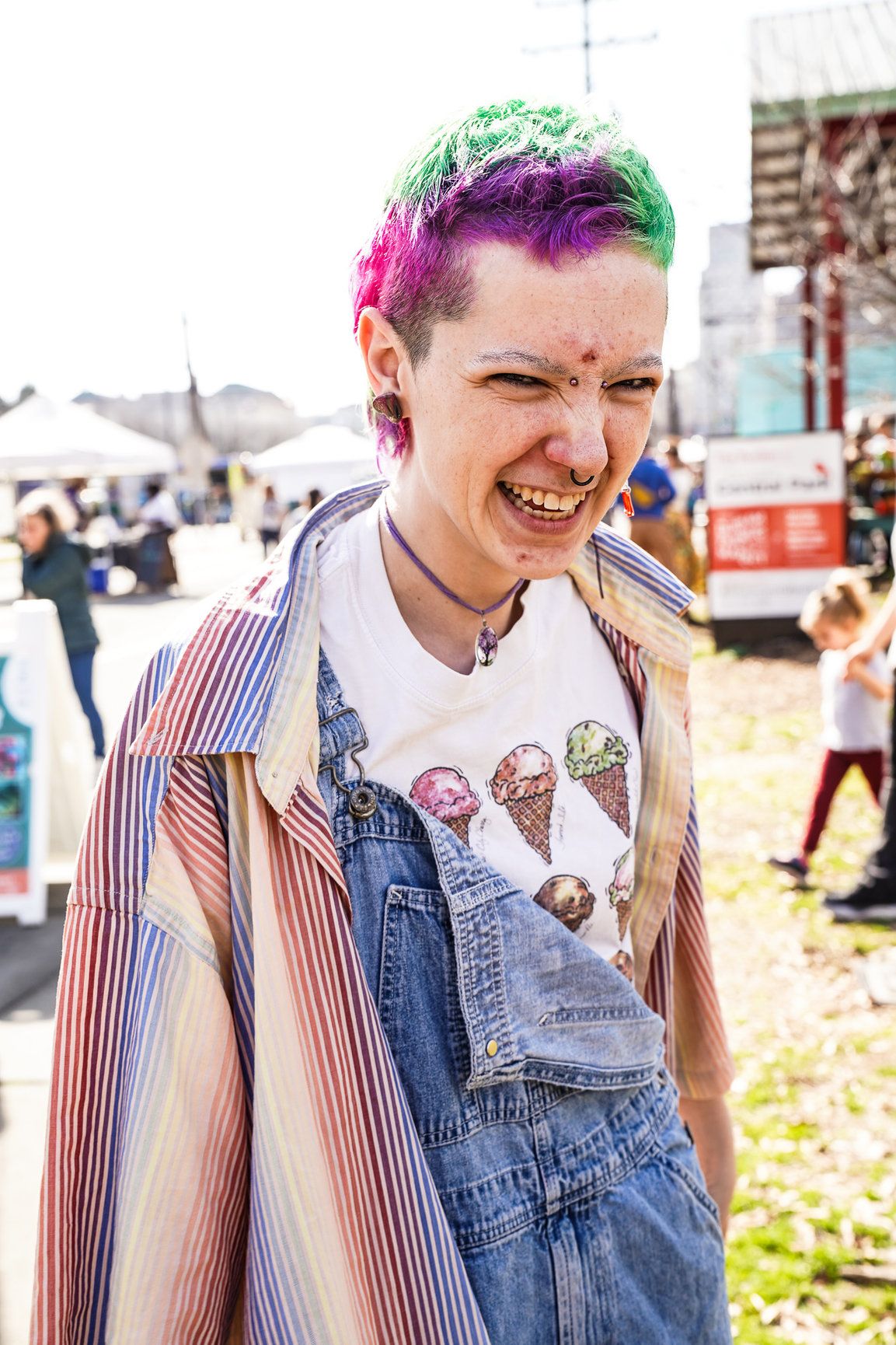 A woman with a nose ring and colorful hair smiles while wearing an ice cream patterned top in downtown Boulder.