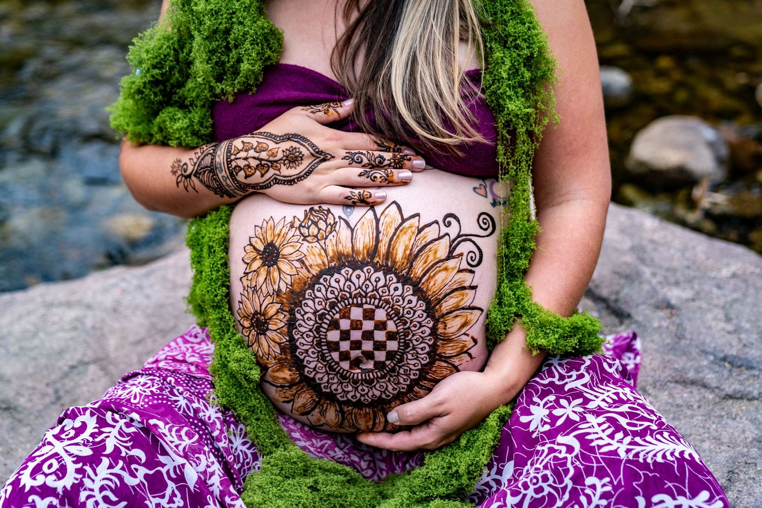 Detailed henna design shown in stages on palm with purple floral fabric background.