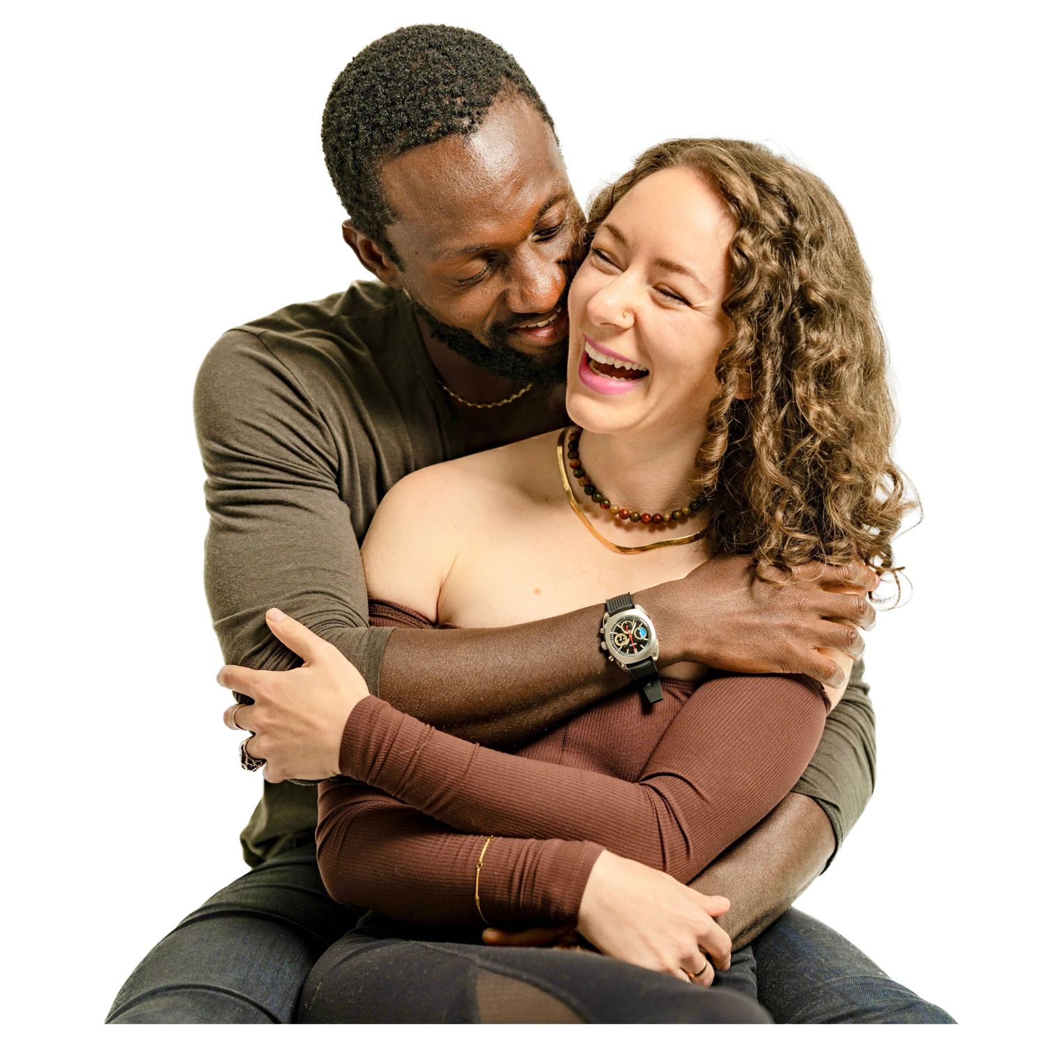 A couple embraces and laughs joyfully together against a white background.