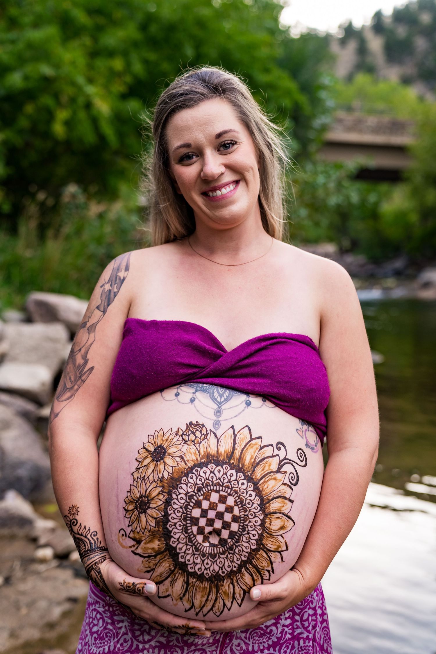 A series of photos showing a pregnant belly with an artistic henna sunflower design against a natural outdoor backdrop.